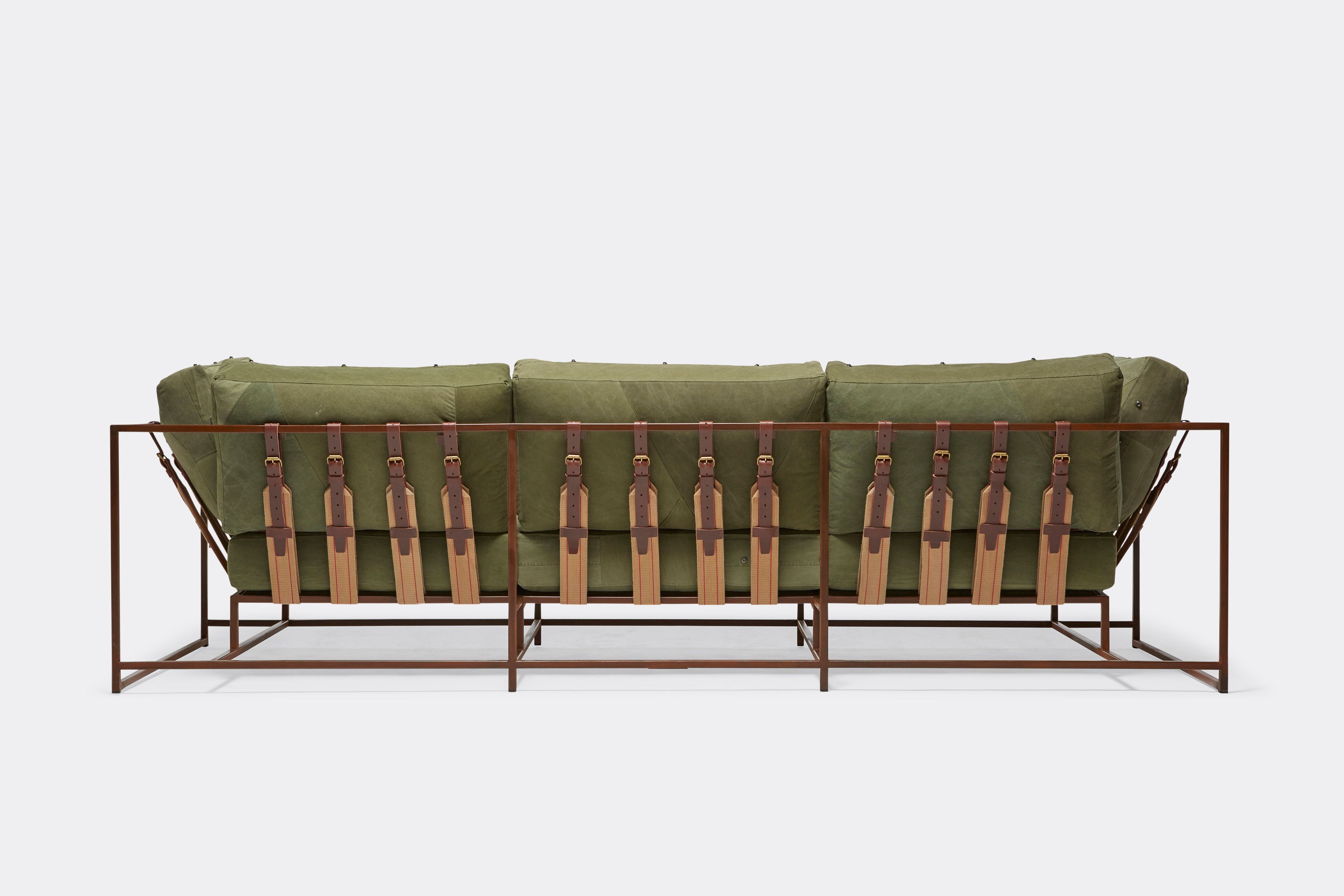 back of sofa with green canvas upholstery and brown belts on marbled rust metal frame