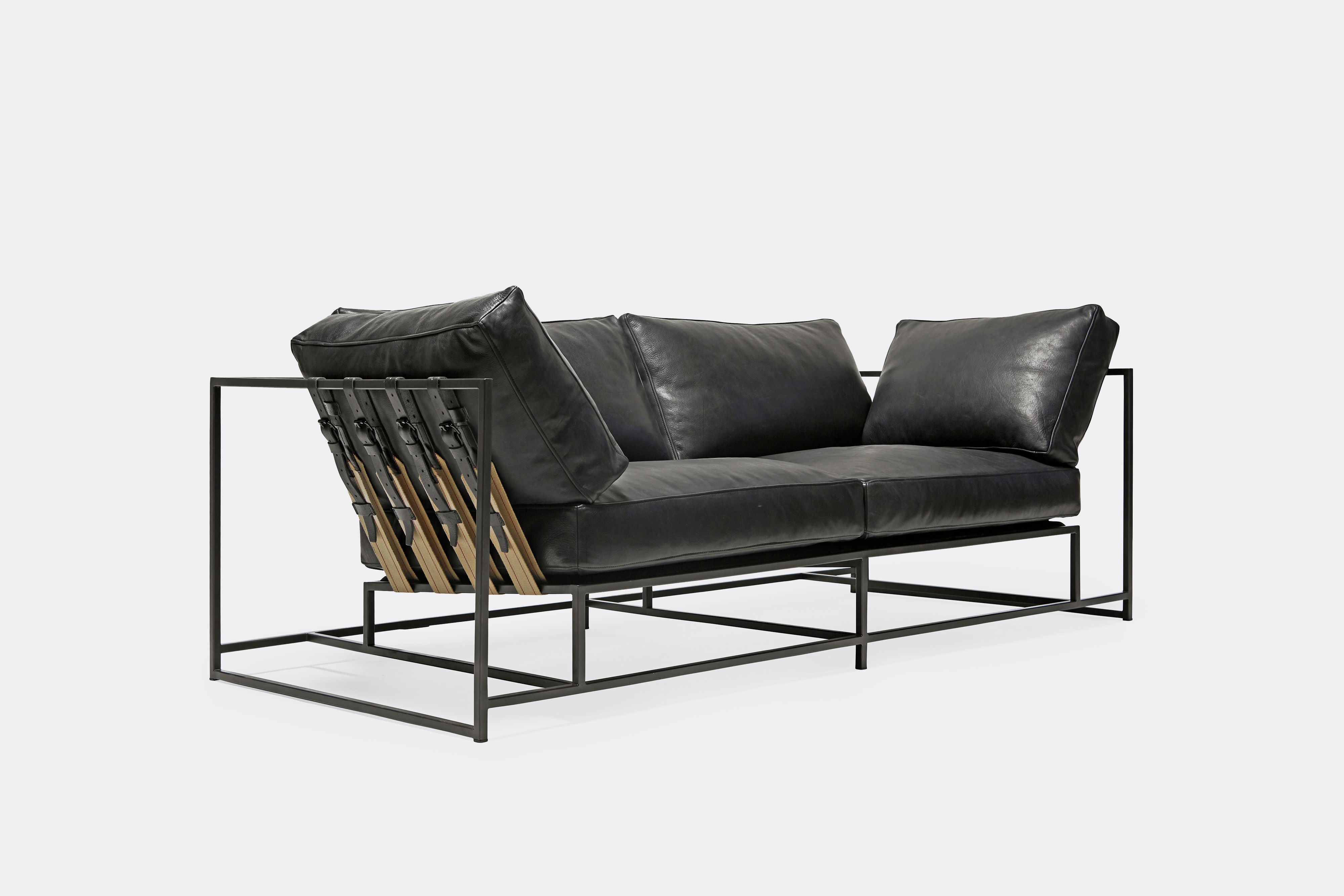 side of two seat sofa black leather upholstery and black leather belts on black metal frame