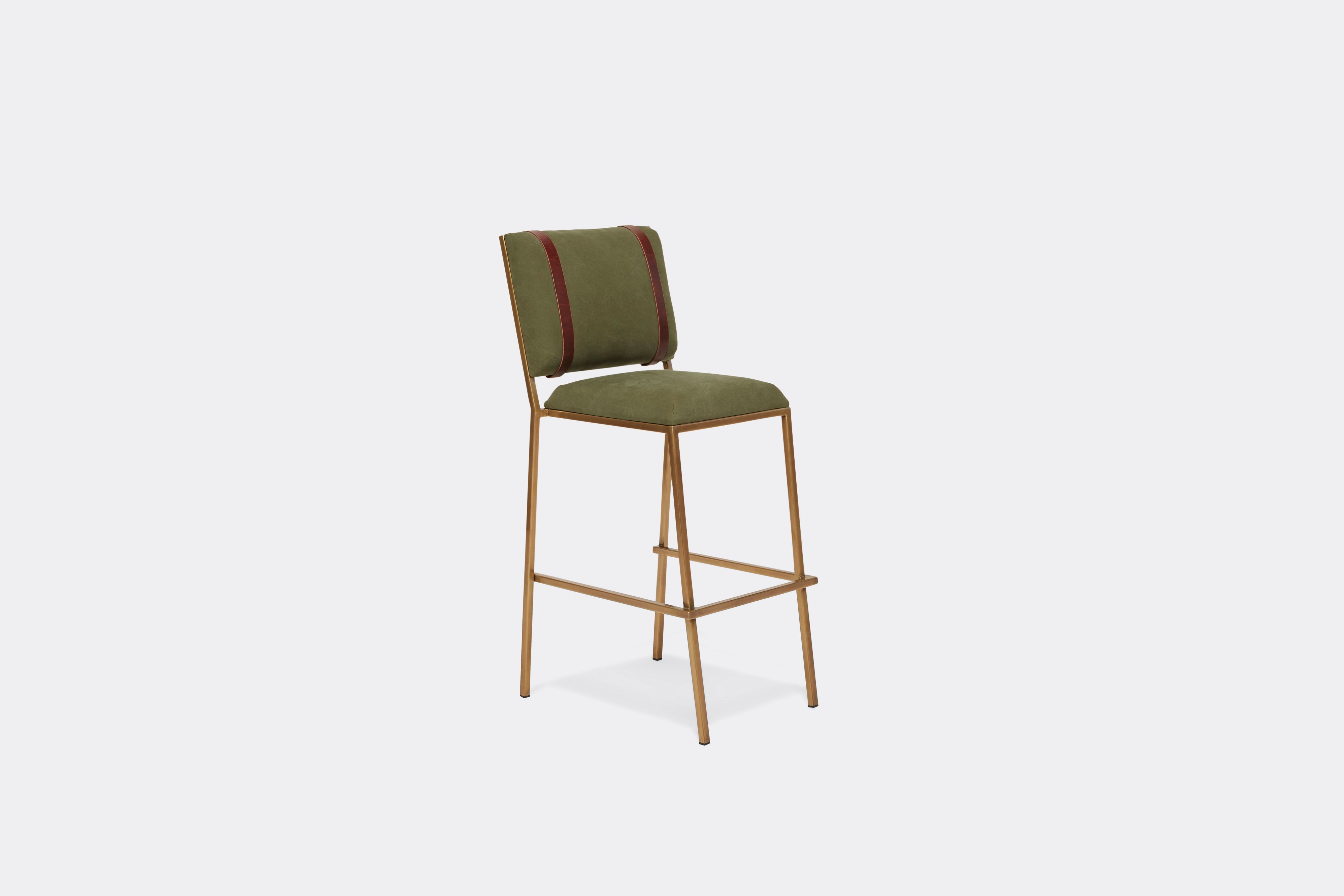 Sideview of barstool with military canvas upholstery and brown leather belts on antique brass metal legs