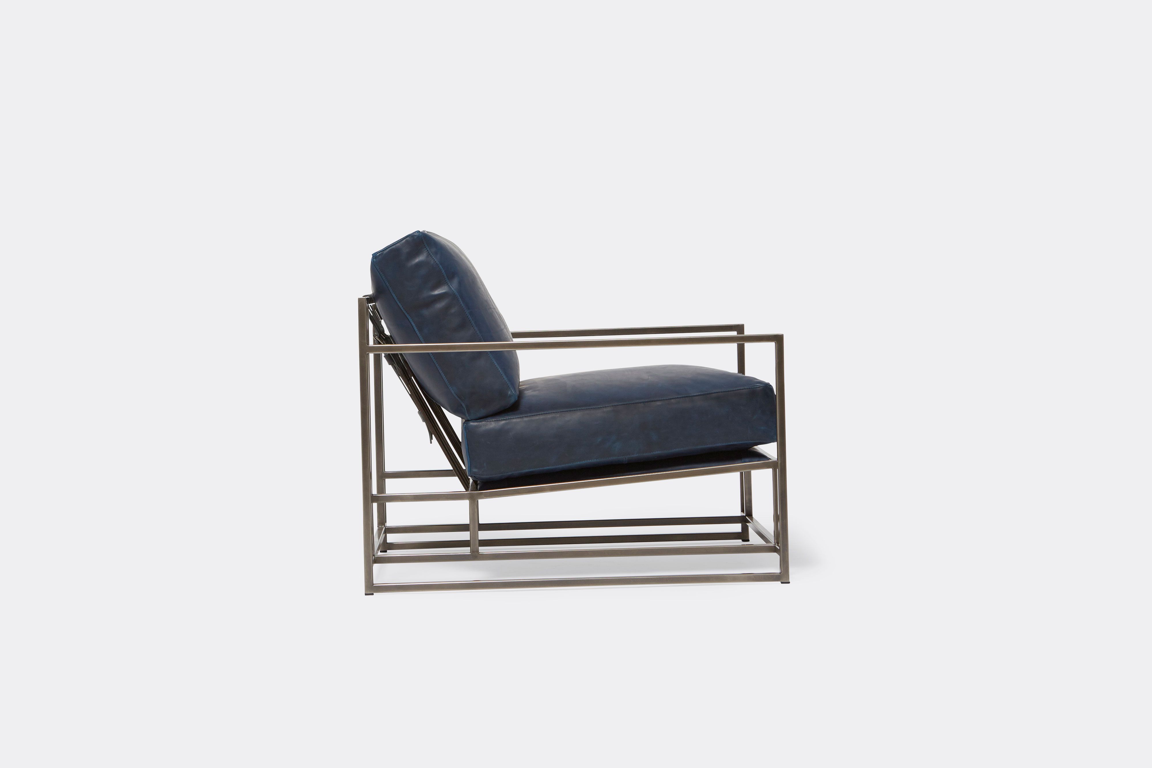 a navy blue leather armchair with a black steel frame and black supporting belts shown on a white background .