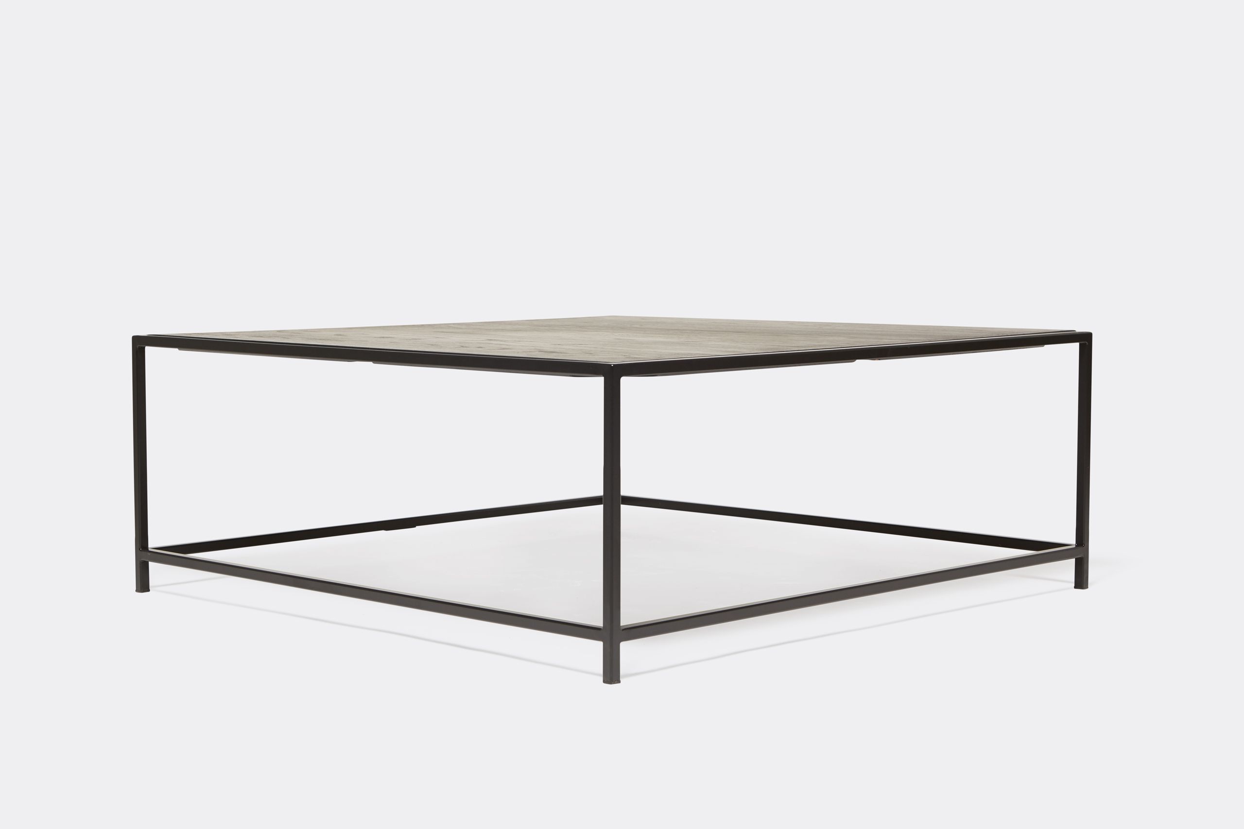 a black wood topped coffee table with a metal frame on a white background .