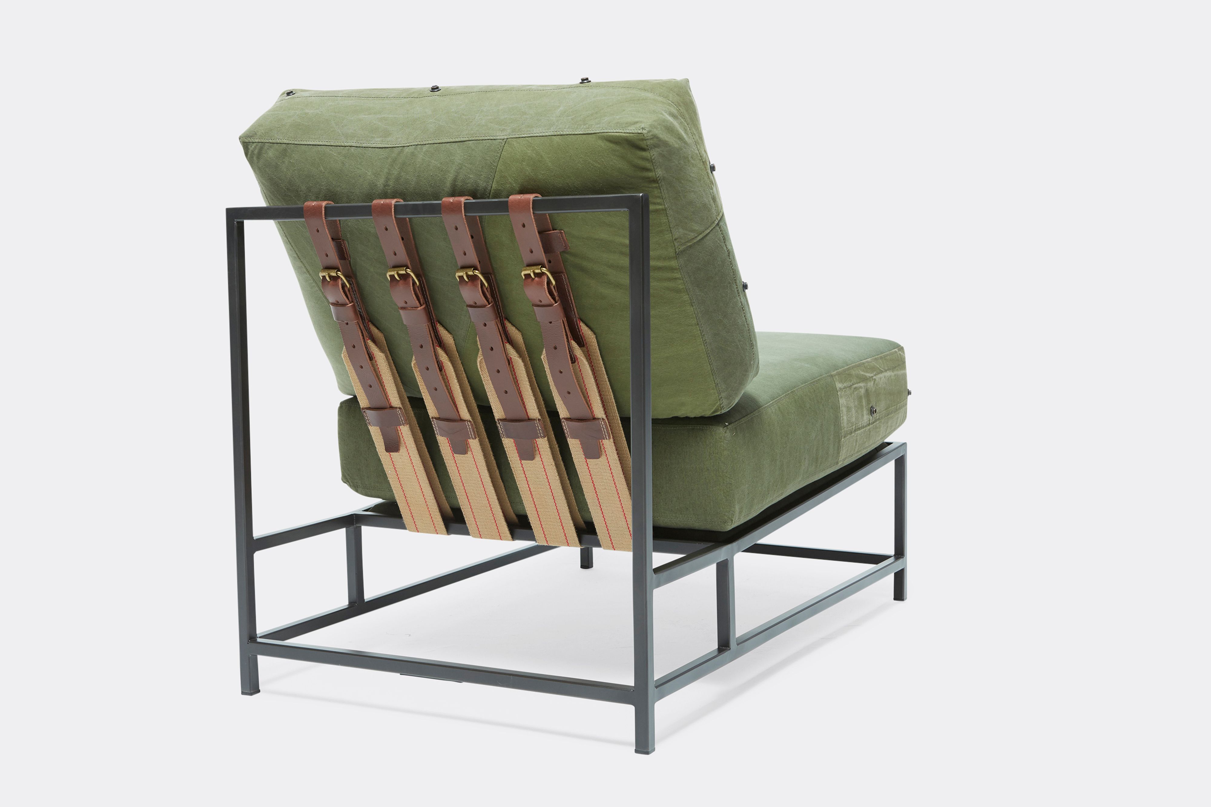 Back of lounge chair with military canvas upholstery and brown leather belts on black metal frame