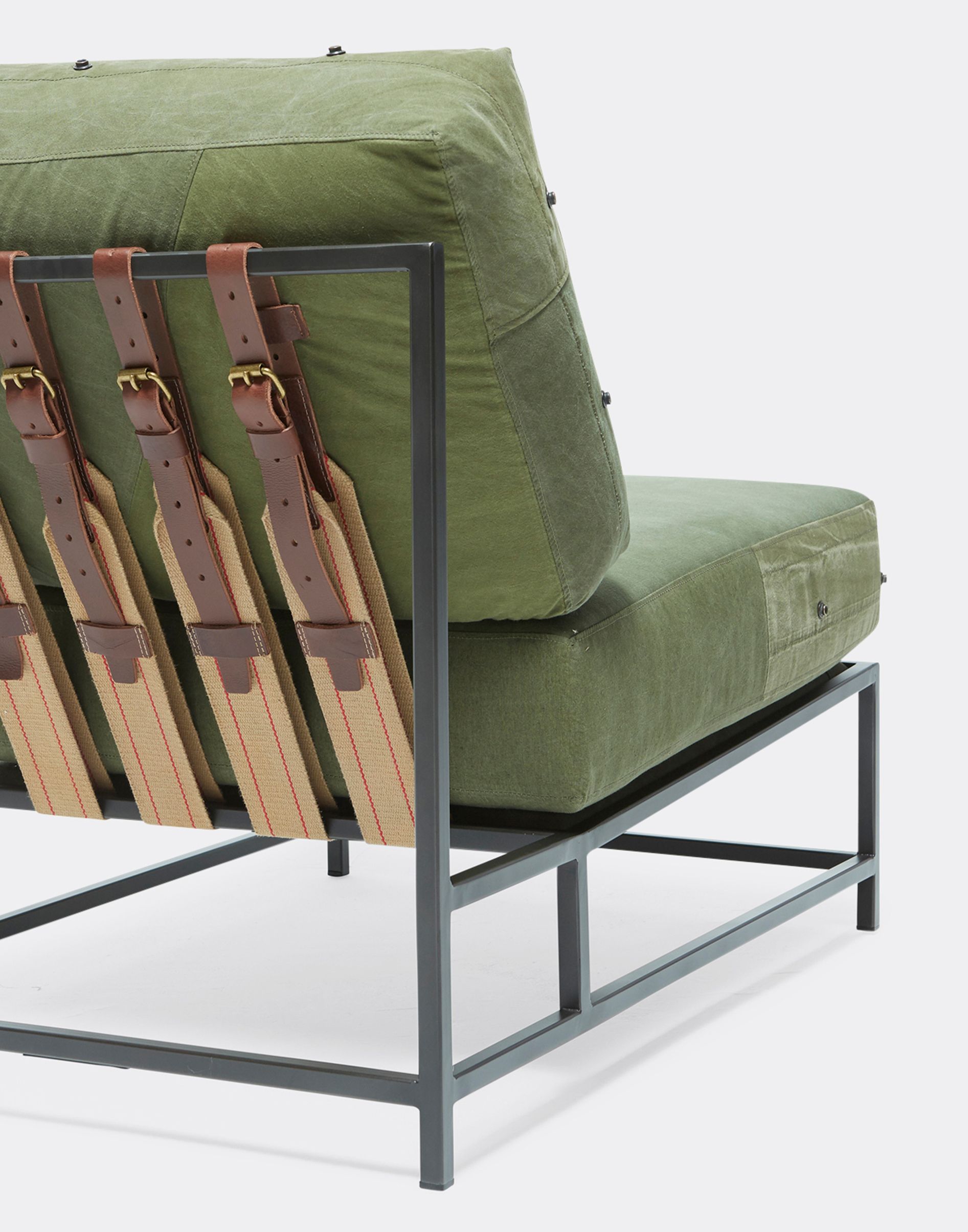 a steel framed chair with a green cushion and leather straps on a white background 