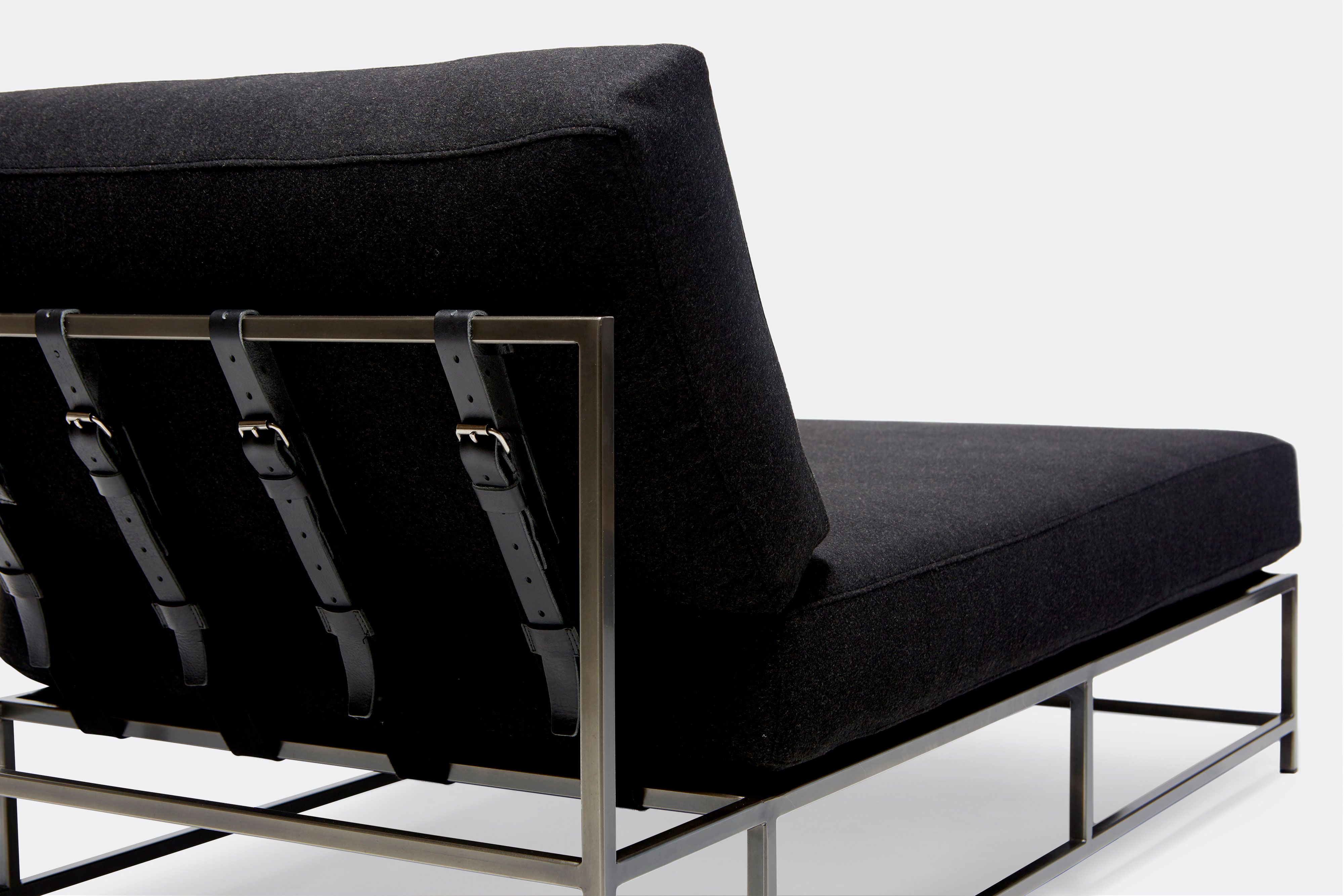 back of chaise lounge with black wool upholstery and black leather belts on antique nickel metal frame