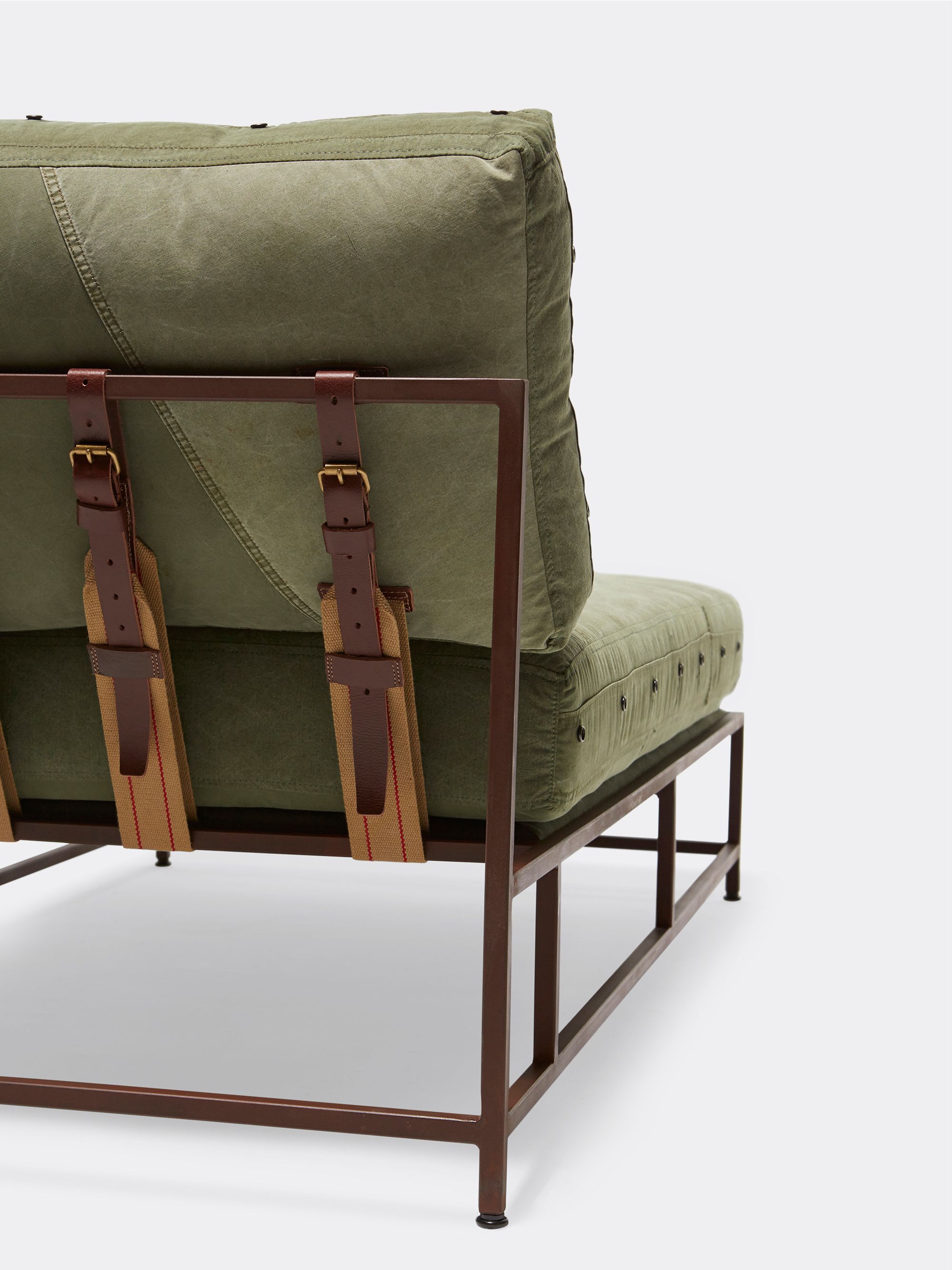 a green canvas and brown finished steel frame chaise lounge with brown leather supporting belts shown on a white background