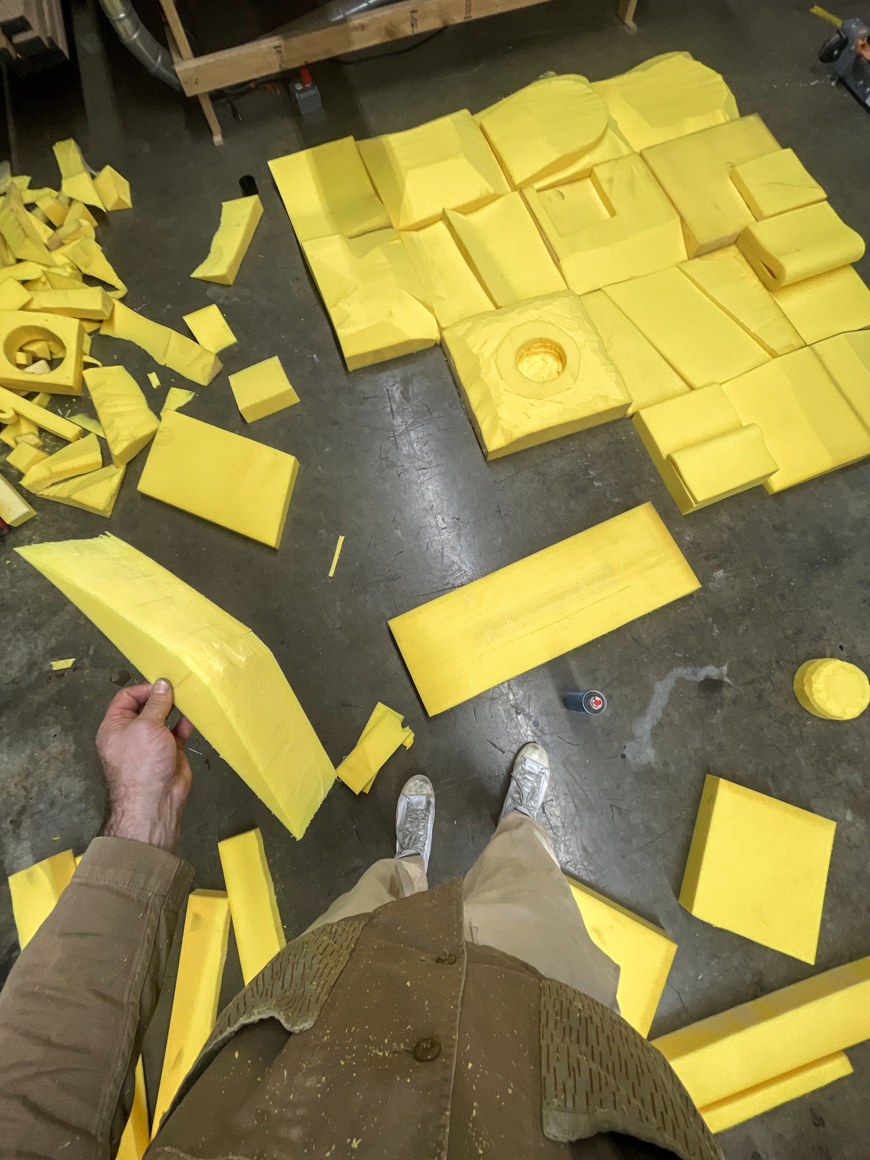 a person is standing in front of a pile of yellow foam pieces