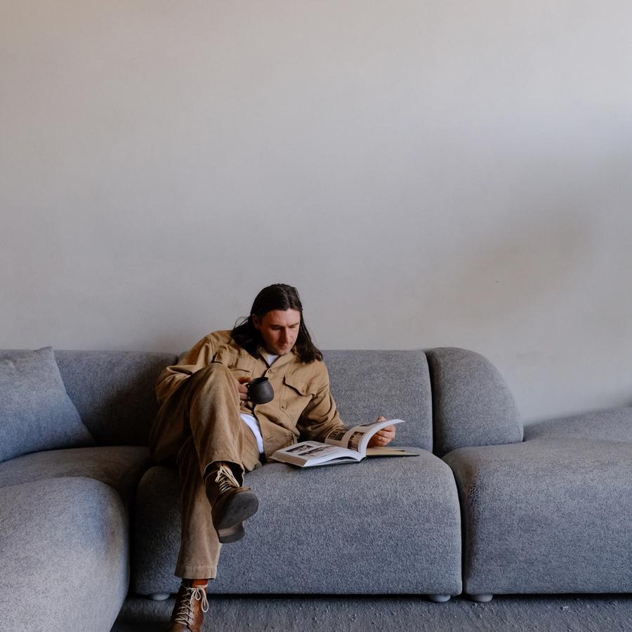 a man is sitting on a couch reading a book .