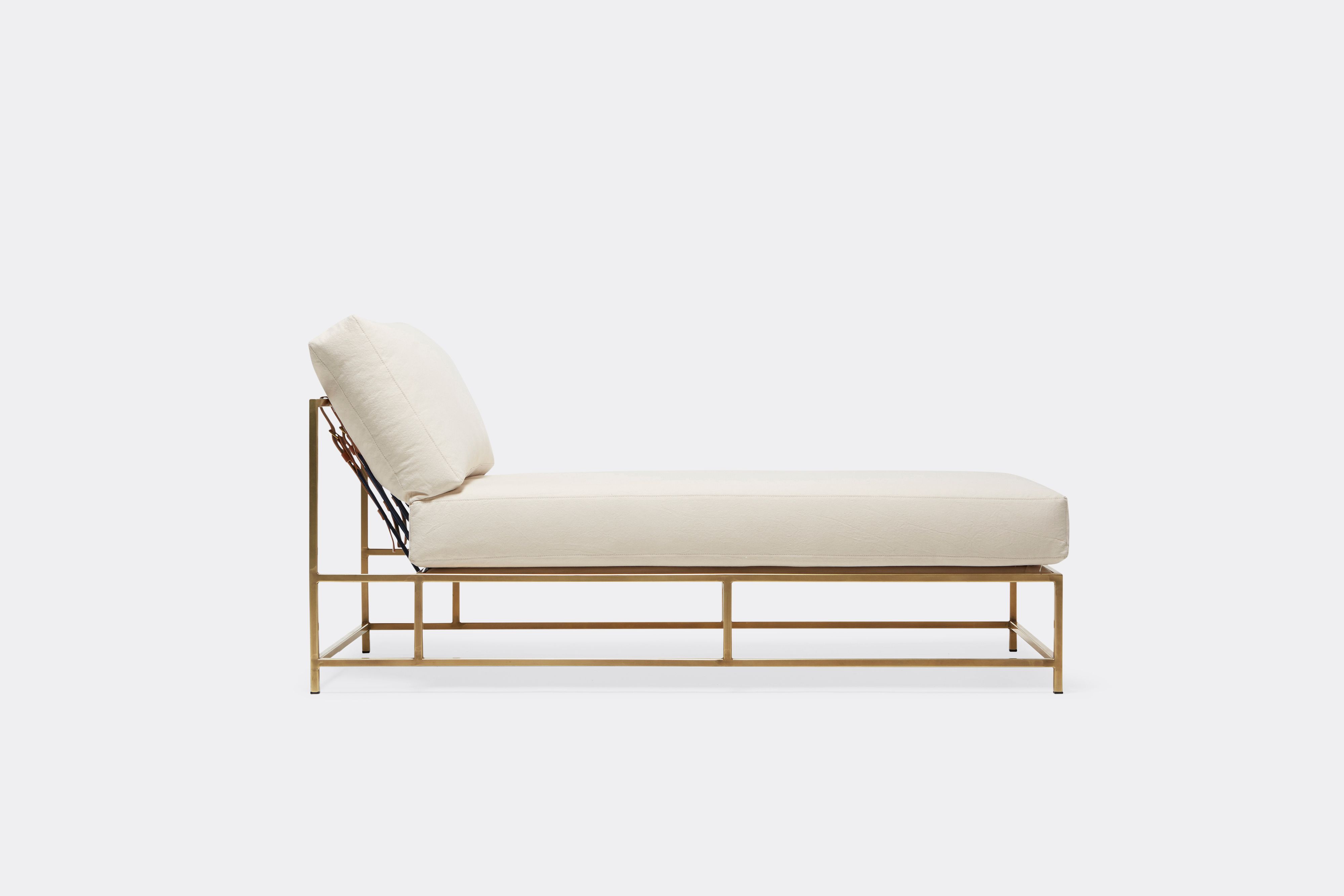 Natural canvas upholstered chaise lounge on antique brass finished frame with leather and webbing supporting belts shown on a white background