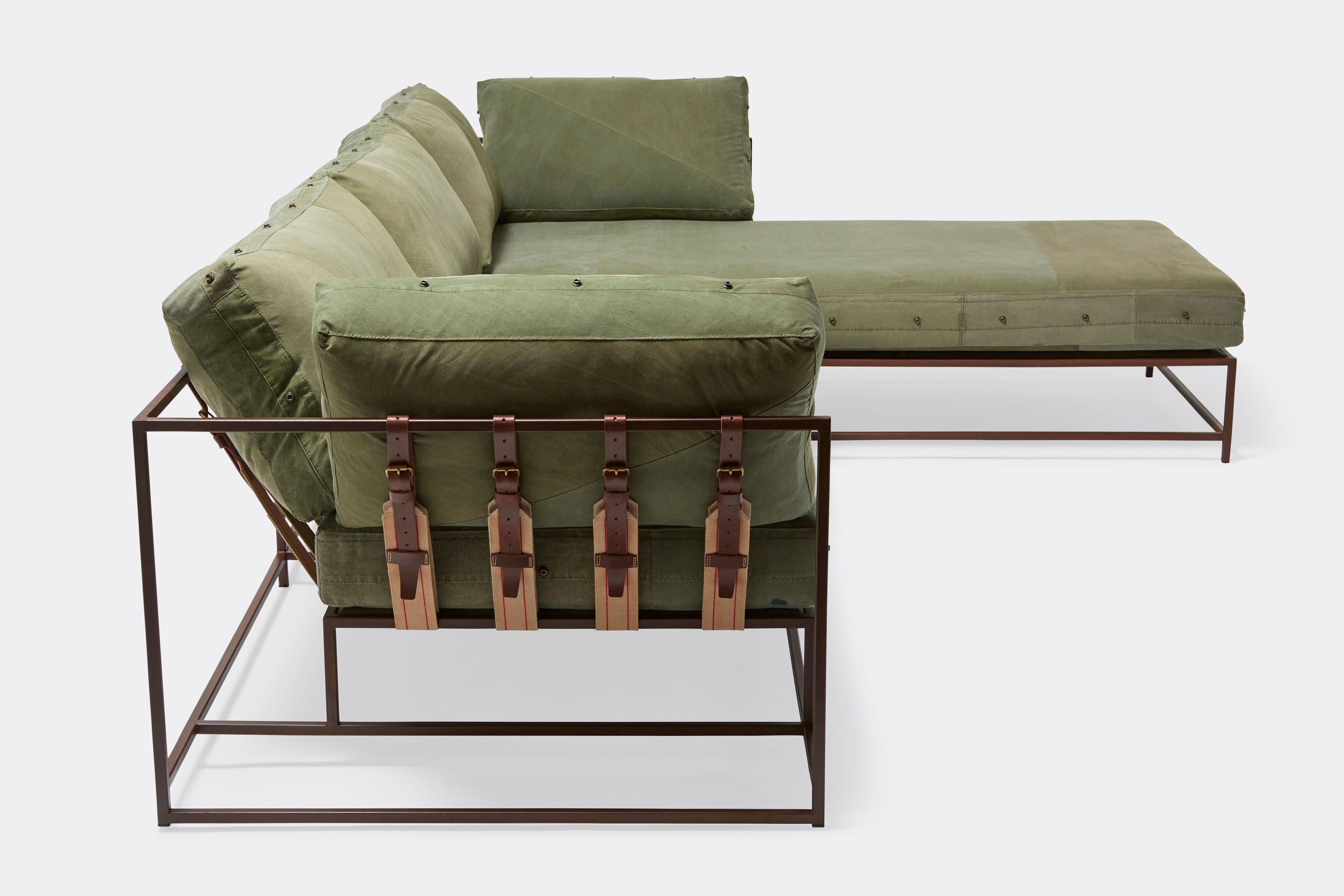 a green canvas sectional sofa with a steel frame and supporting belts shown on a white background .