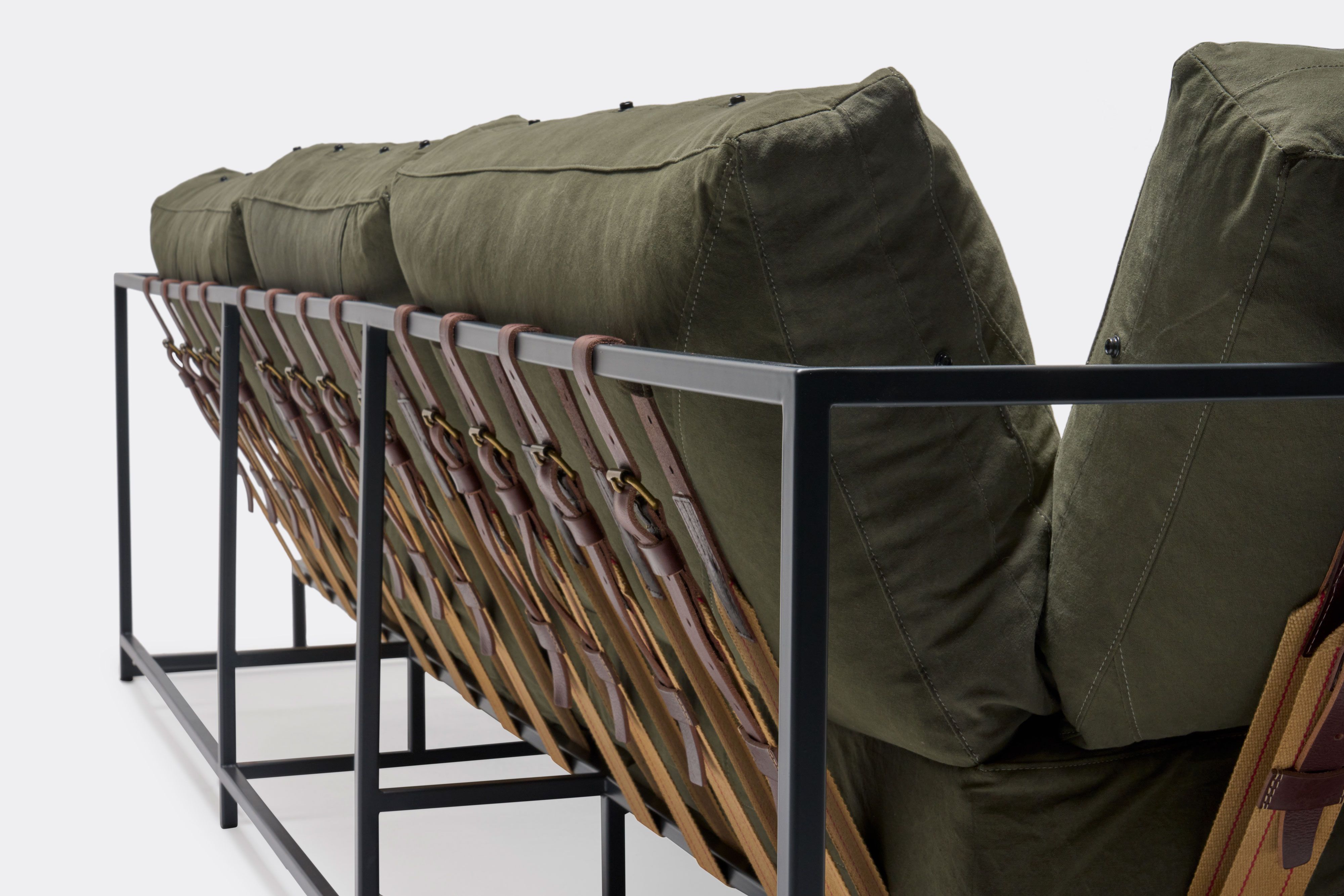 a green couch with a metal frame and leather straps