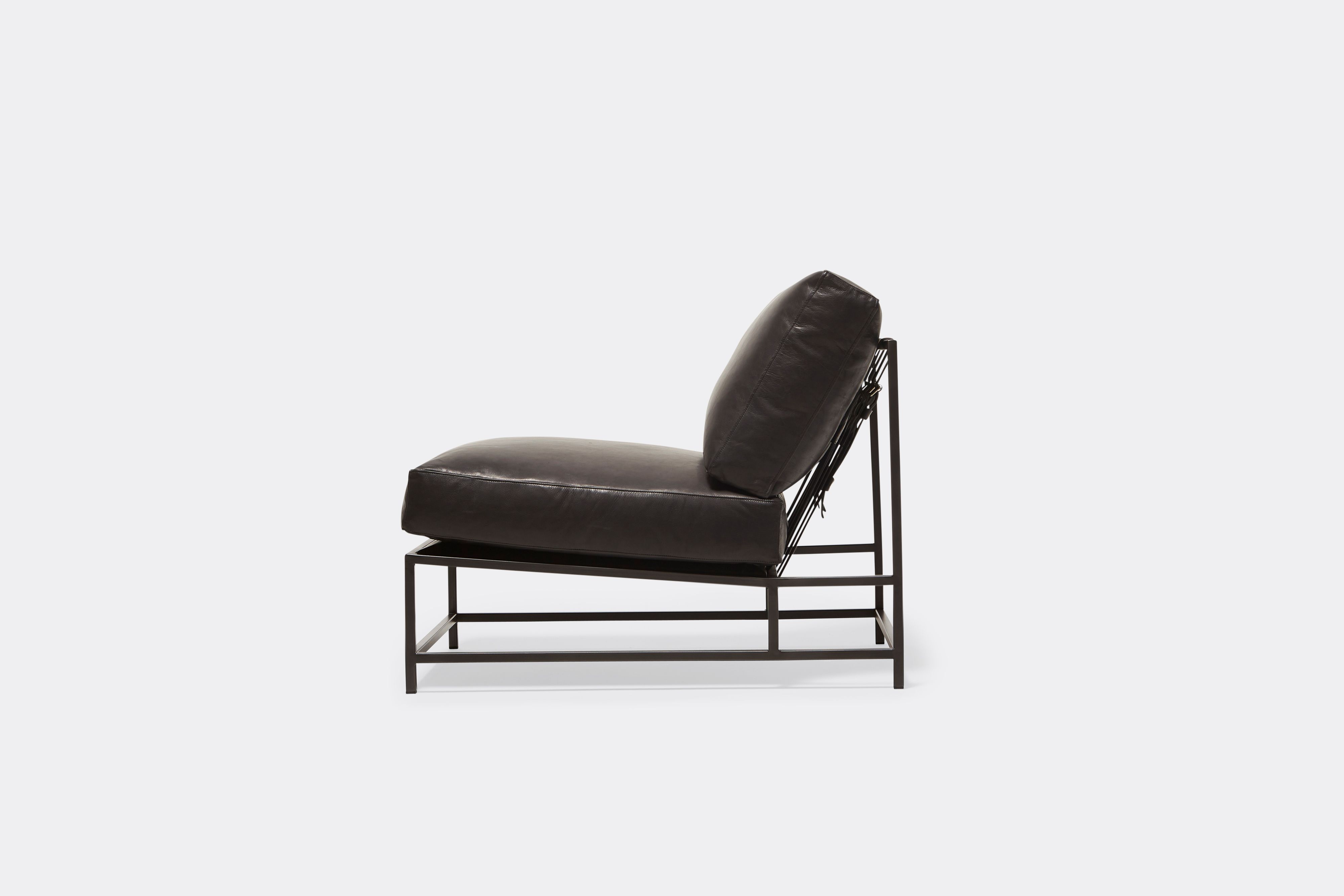 Sideview of lounge chair withblack leather upholstery and black metal frame