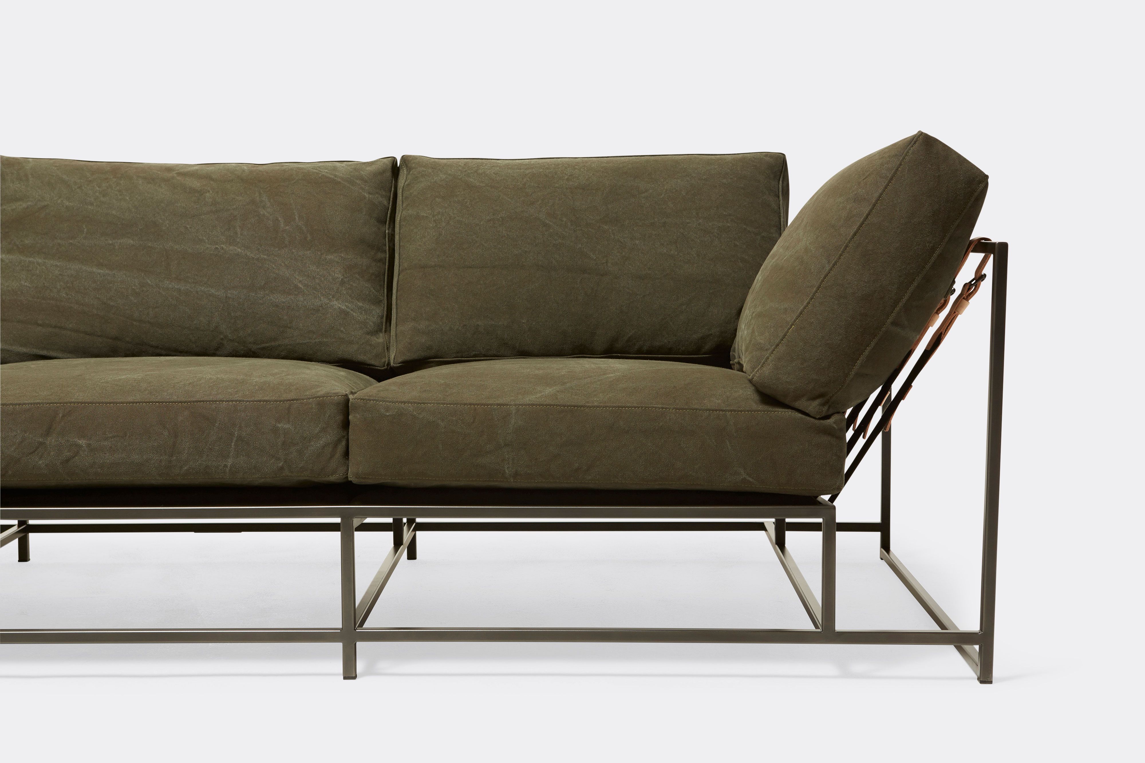 detail front of sofa with green canvas upholstery on black metal frame