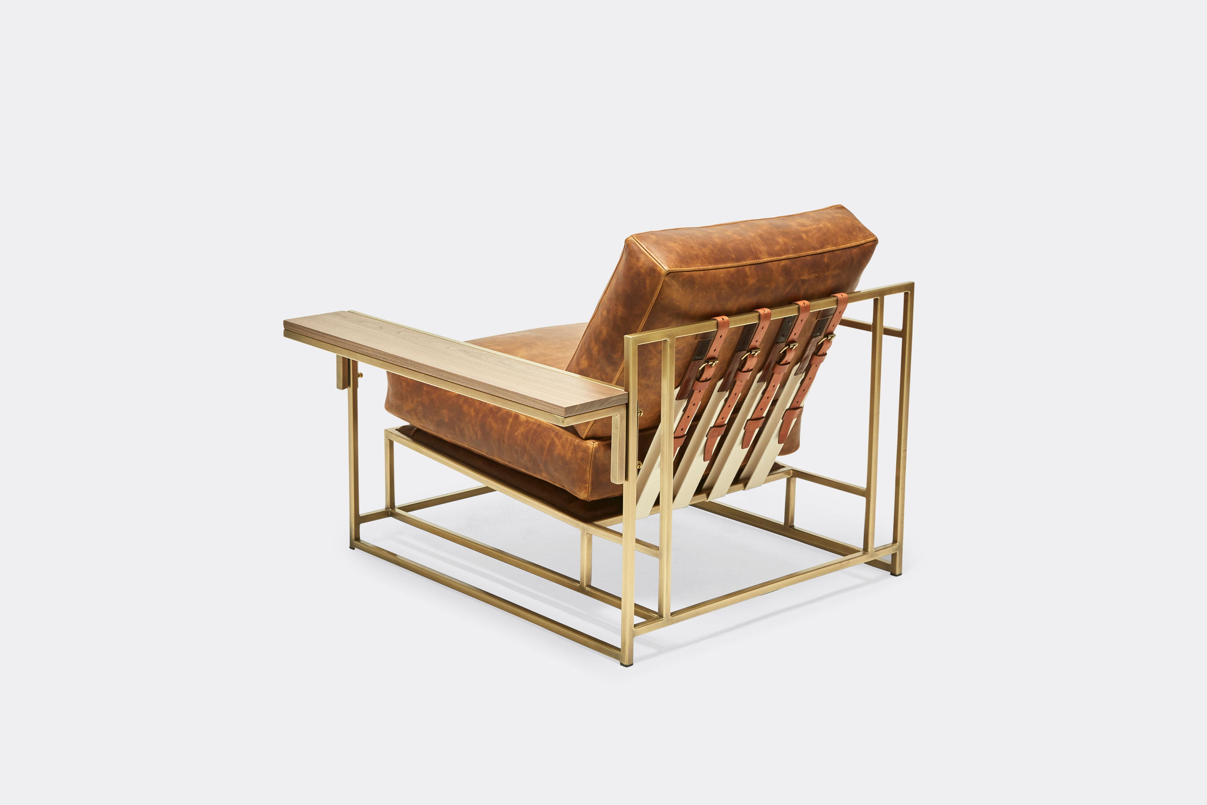 back of armchair with brown leather upholstery and brown leather belts on antique brass metal frame