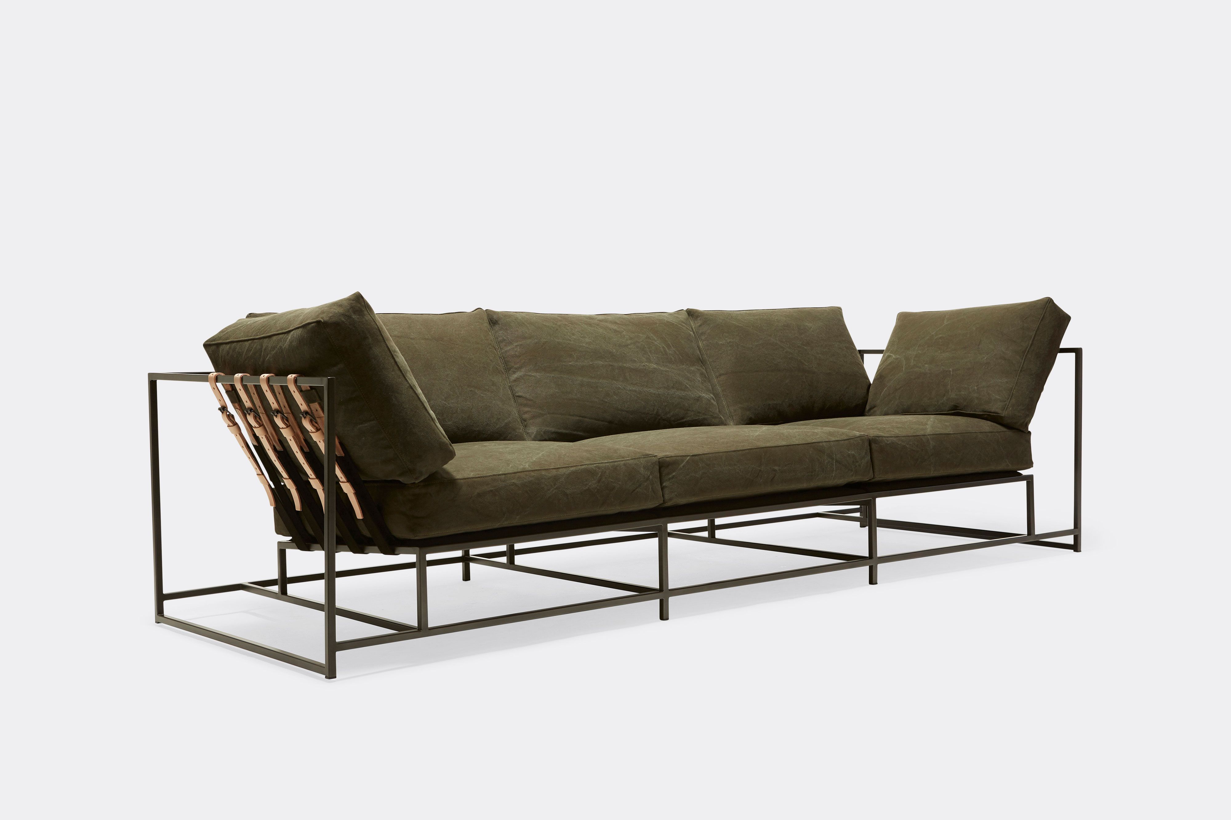 side of sofa with green canvas upholstery and natural leather belts on black metal frame