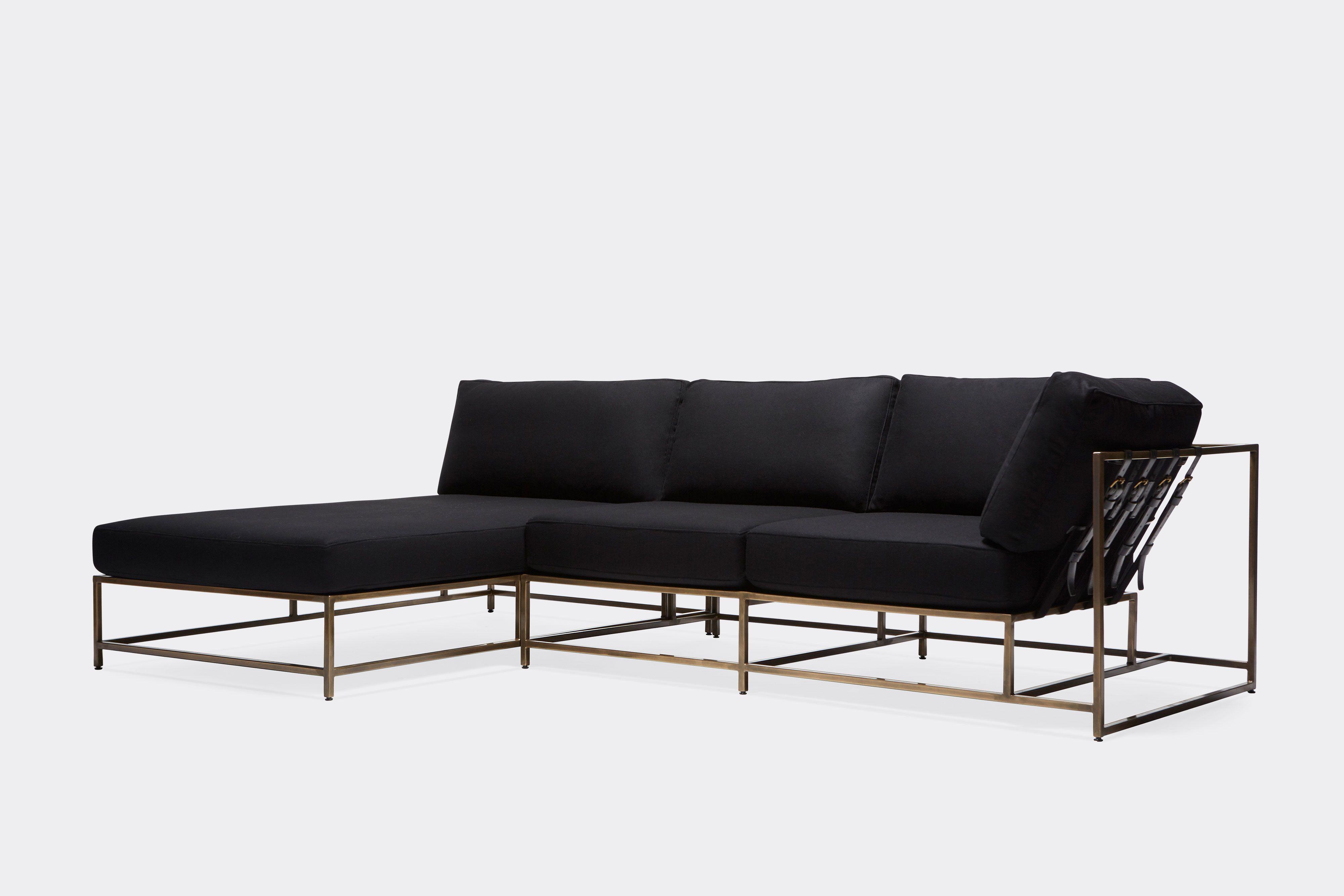 side of sectional with black wool upholstery and black leather belts on antique brass metal frame