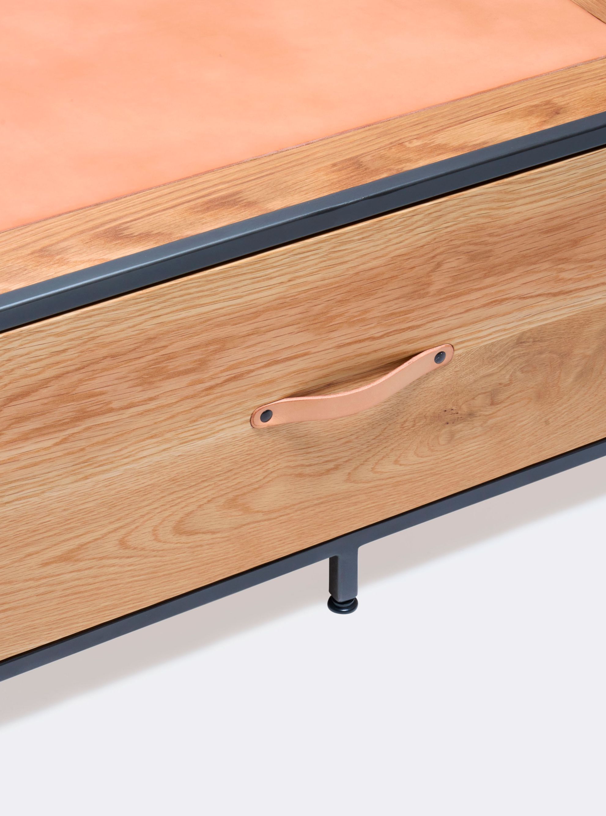 a wooden coffee table with a leather top and a steel frame and two drawers with leather handles shown on a white background