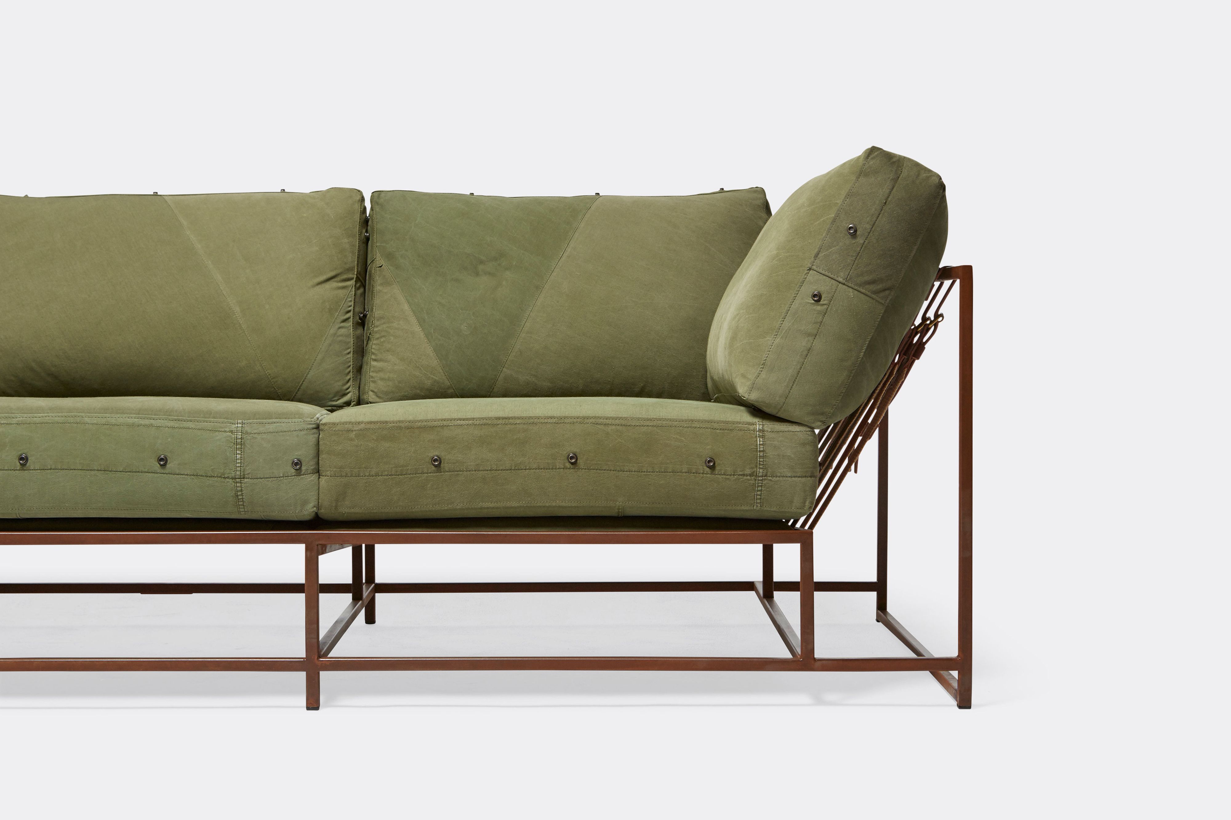 front of sofa with green canvas upholstery on marbled rust metal frame