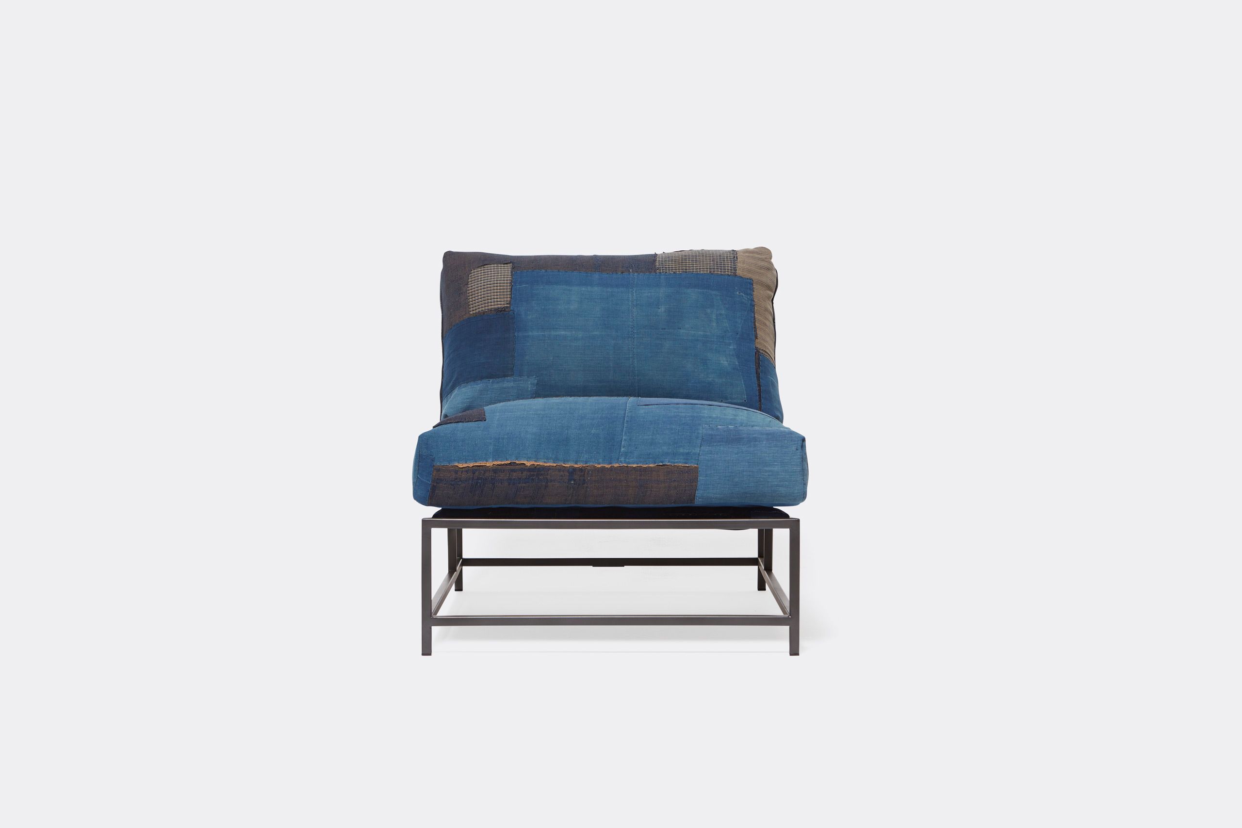 A steel framed chair upholstered with vintage japanese indigo and grey quilted material and blue and black supporting belts shown on a white background