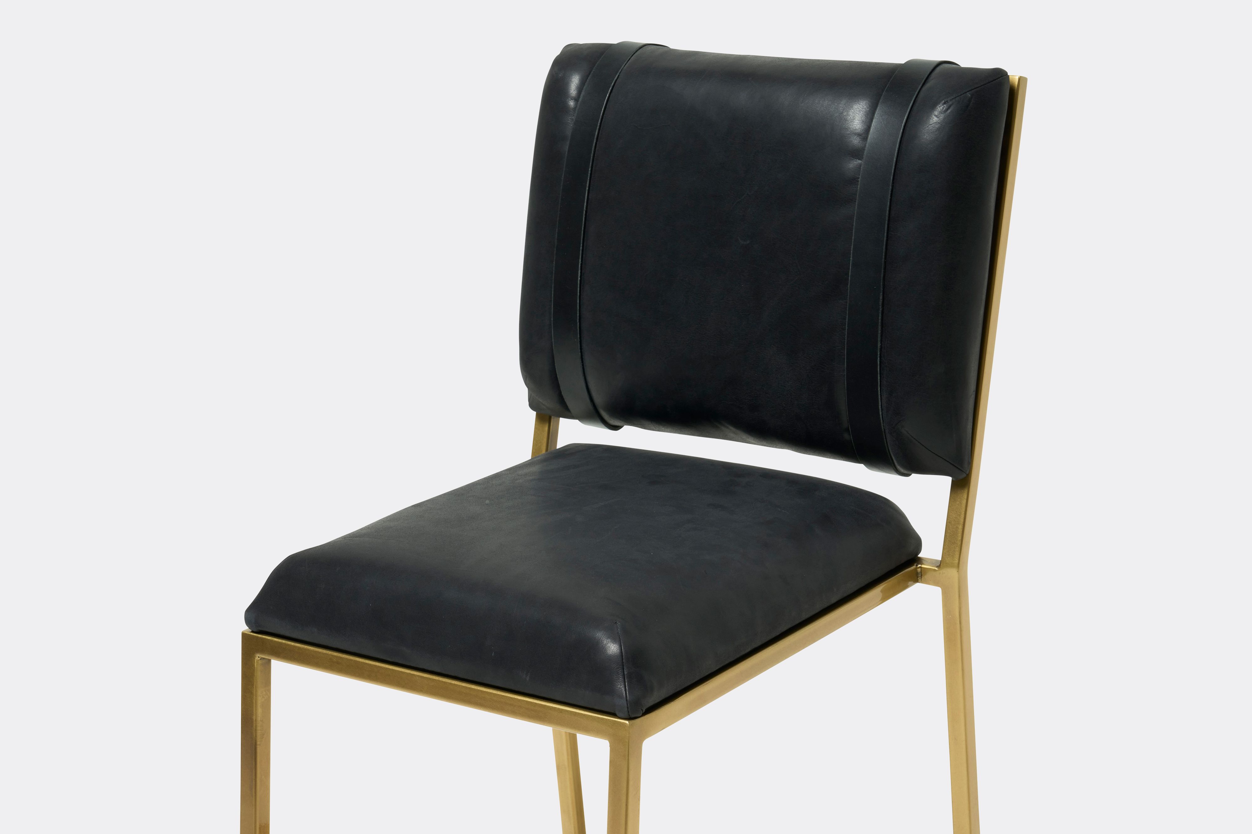 Close up view of black leather barstool with antique brass metal frame
