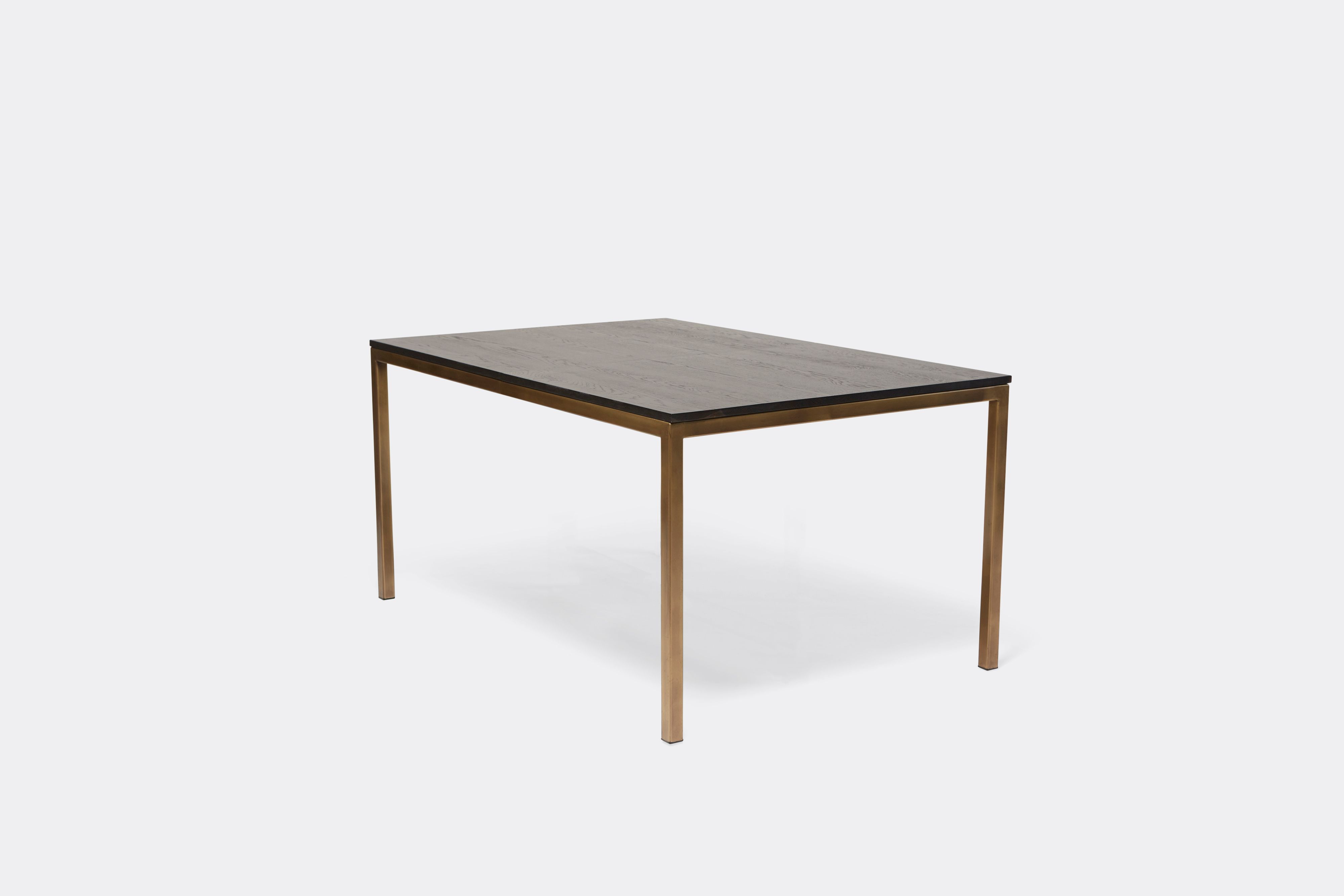 Sideview of dining table with ebonized oak wood top and antique brass metal legs