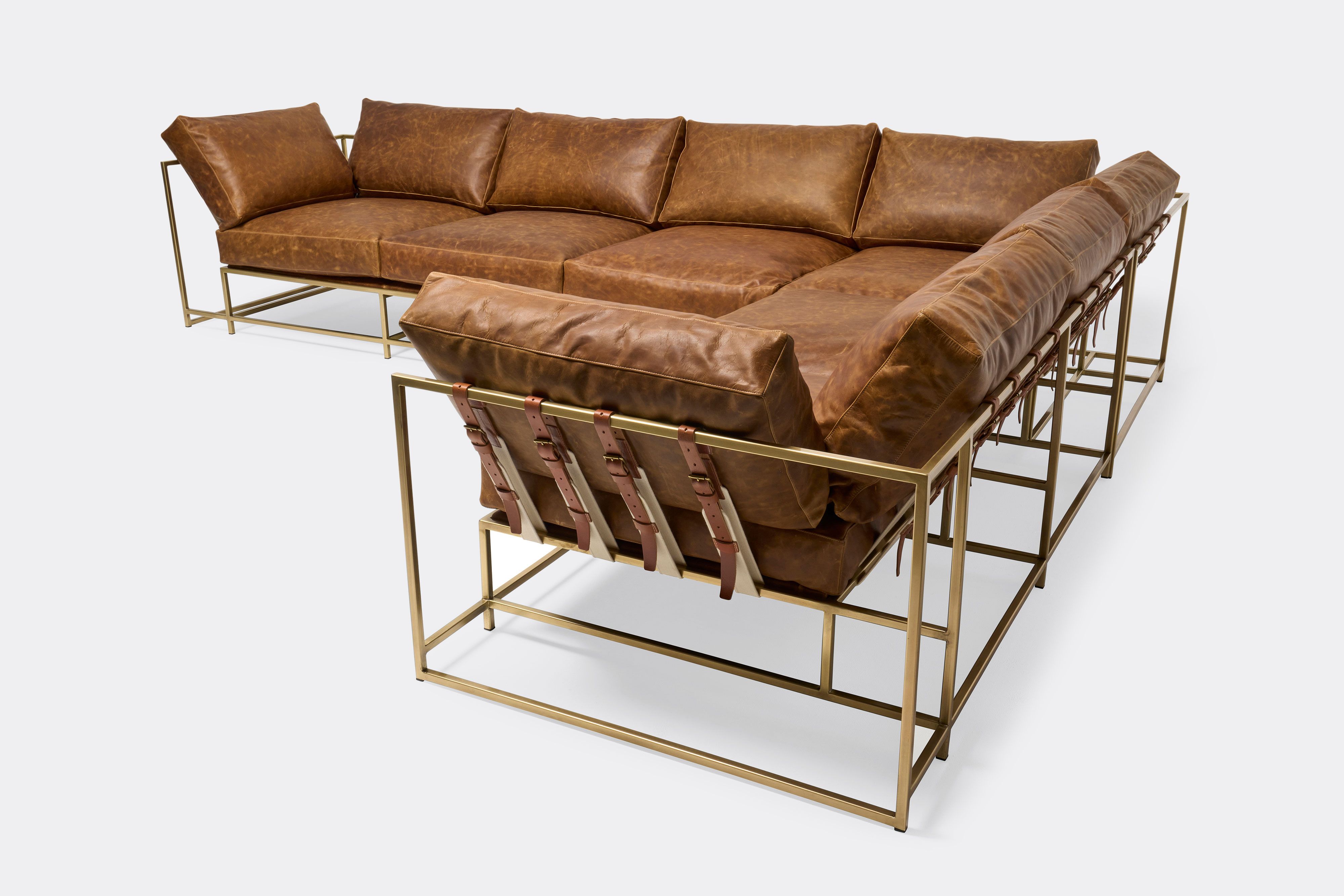 overhead of sectional with tan leather upholstery and brown leather belts on antique brass metal frame