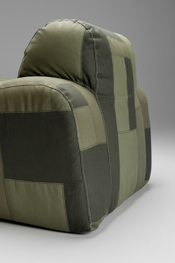 An upholstered armchair in olive green patchwork fabric with visible stitching.