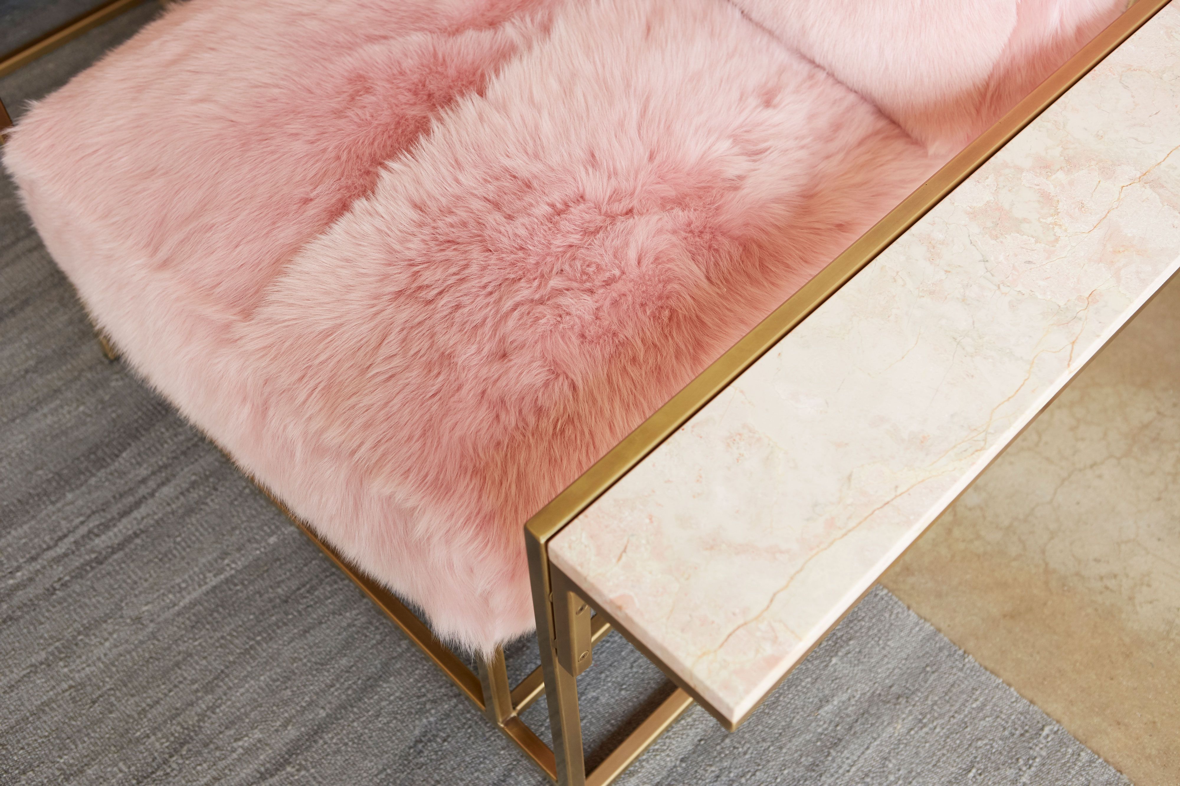 detail of armchair with pink shearing upholstery on antique brass metal frame