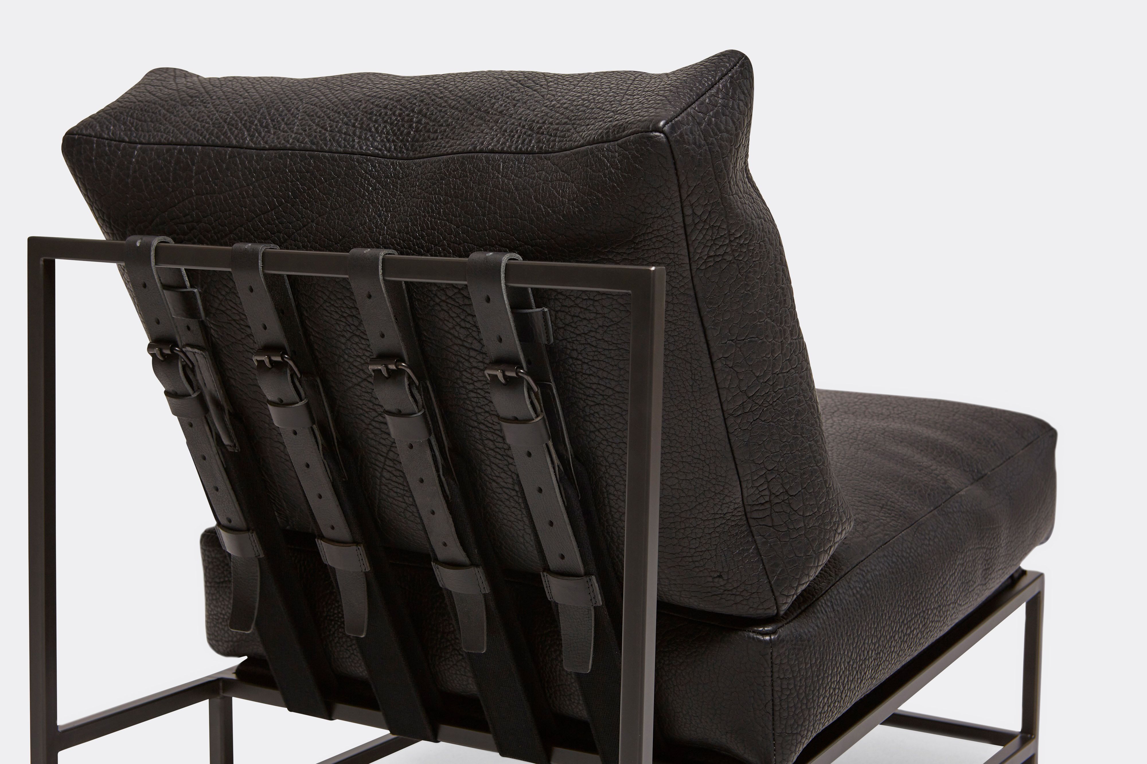 Detail of lounge chair with black leather upholstery and black leather belts on black metal frame