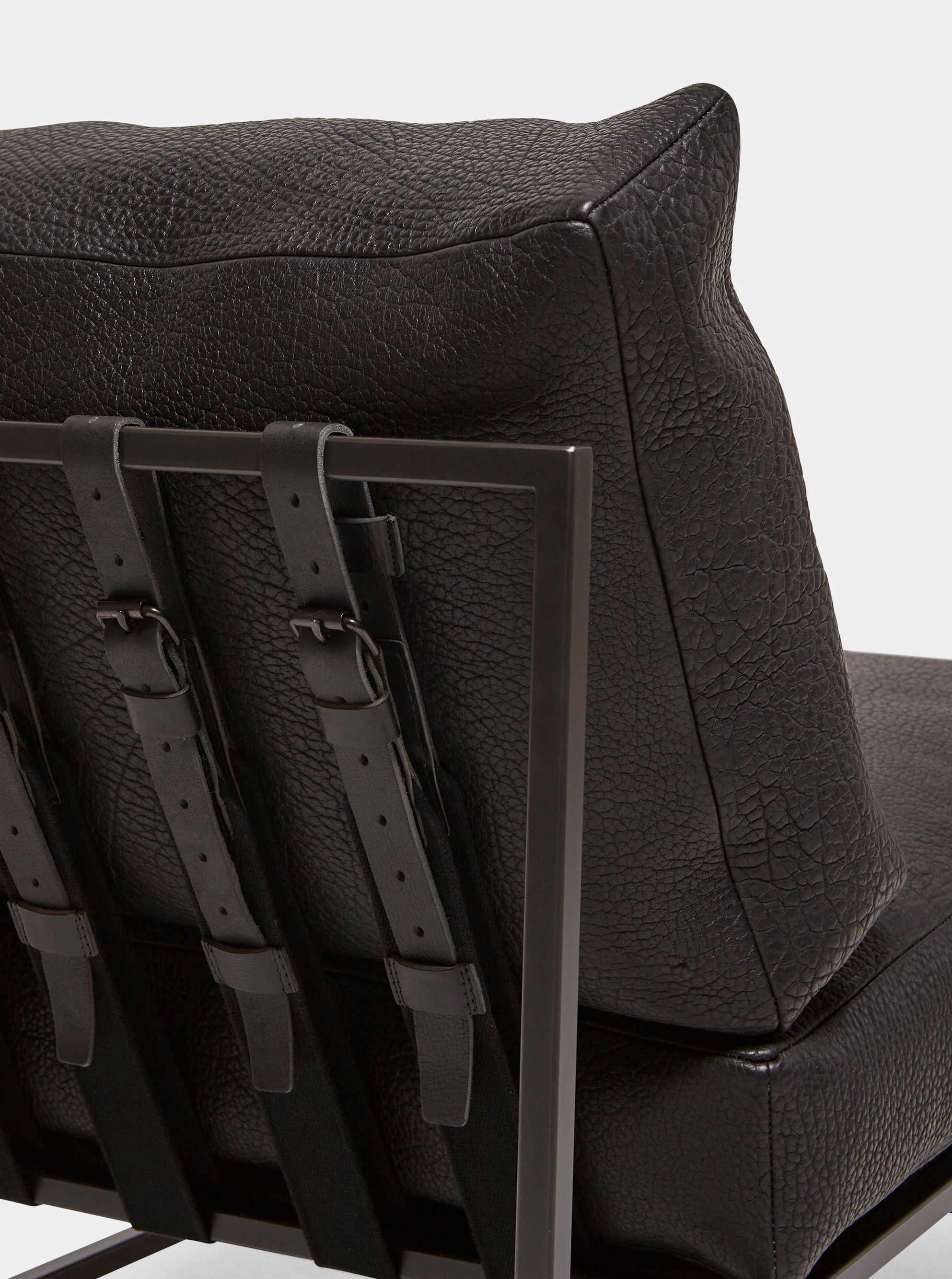 the back of a black leather chair with a metal frame and black supporting belts shown on a white background