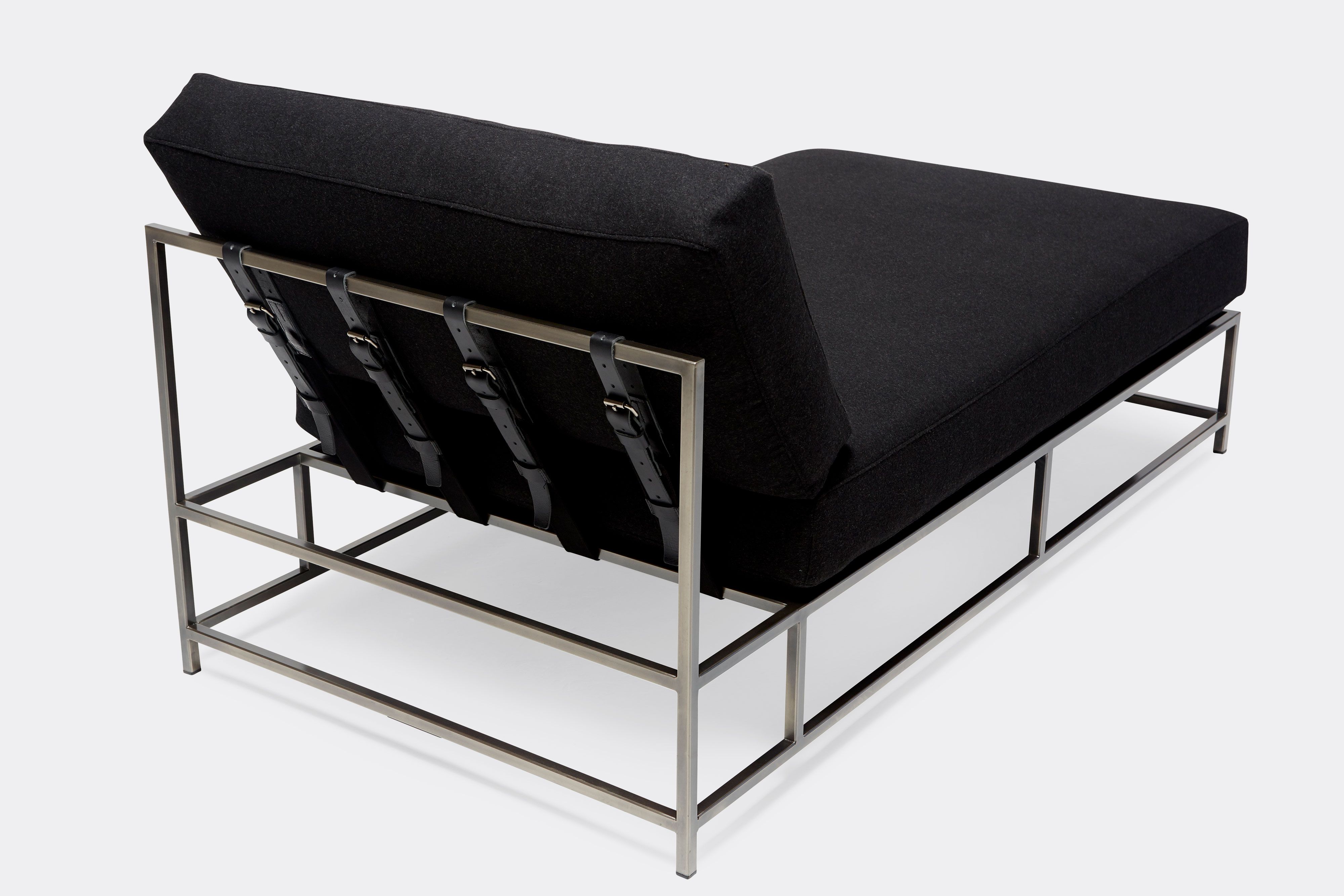 back detail of chaise lounge with black wool upholstery and black leather belts on antique nickel metal frame