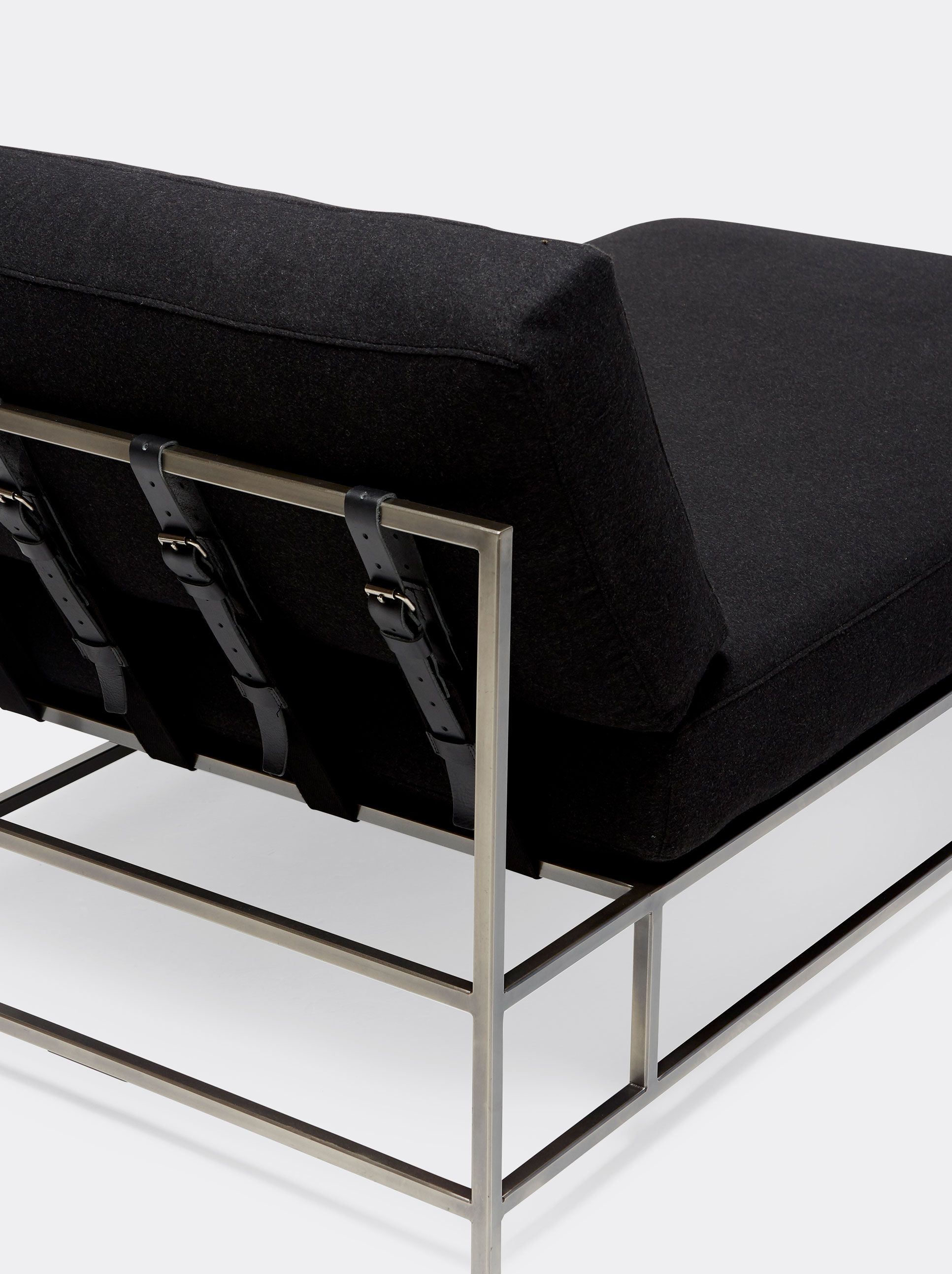  a black chaise lounge with a metal frame and black supporting belts on a white background .
