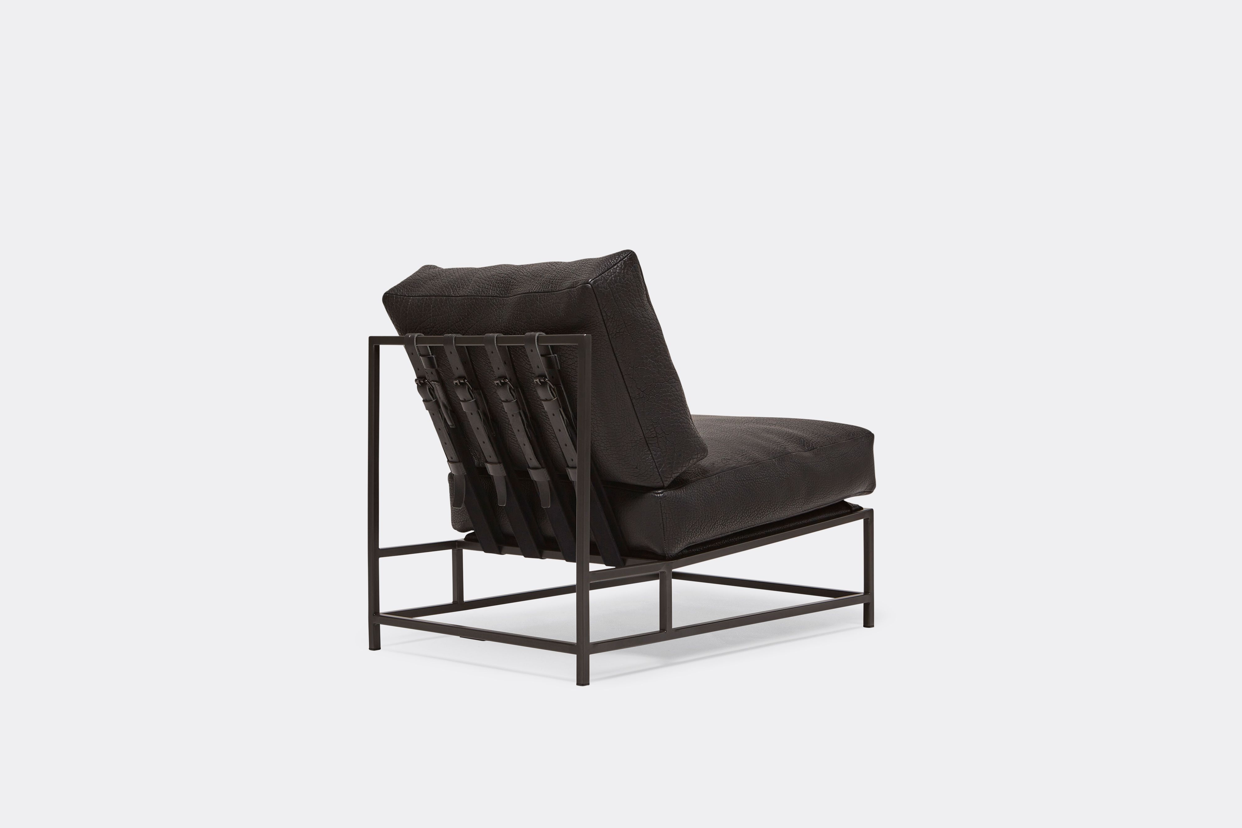Back view of lounge chair with black leather upholstery and black leather belts on black metal frame