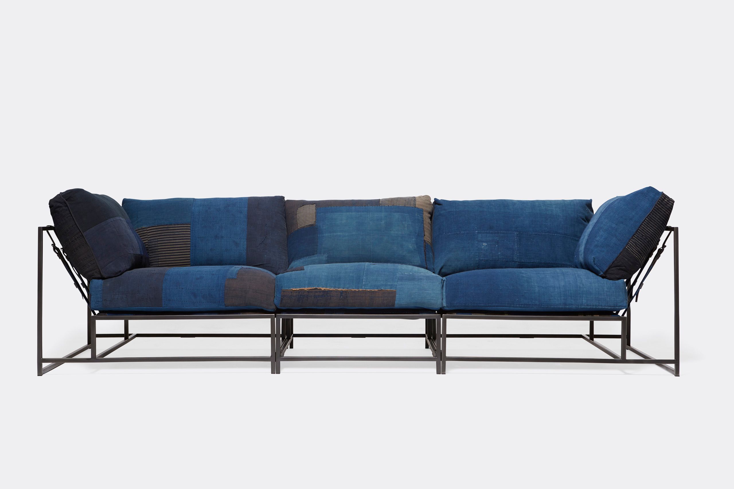 A steel framed sofa with vintage Japanese indigo and grey upholstery and supporting belts shown on a white background