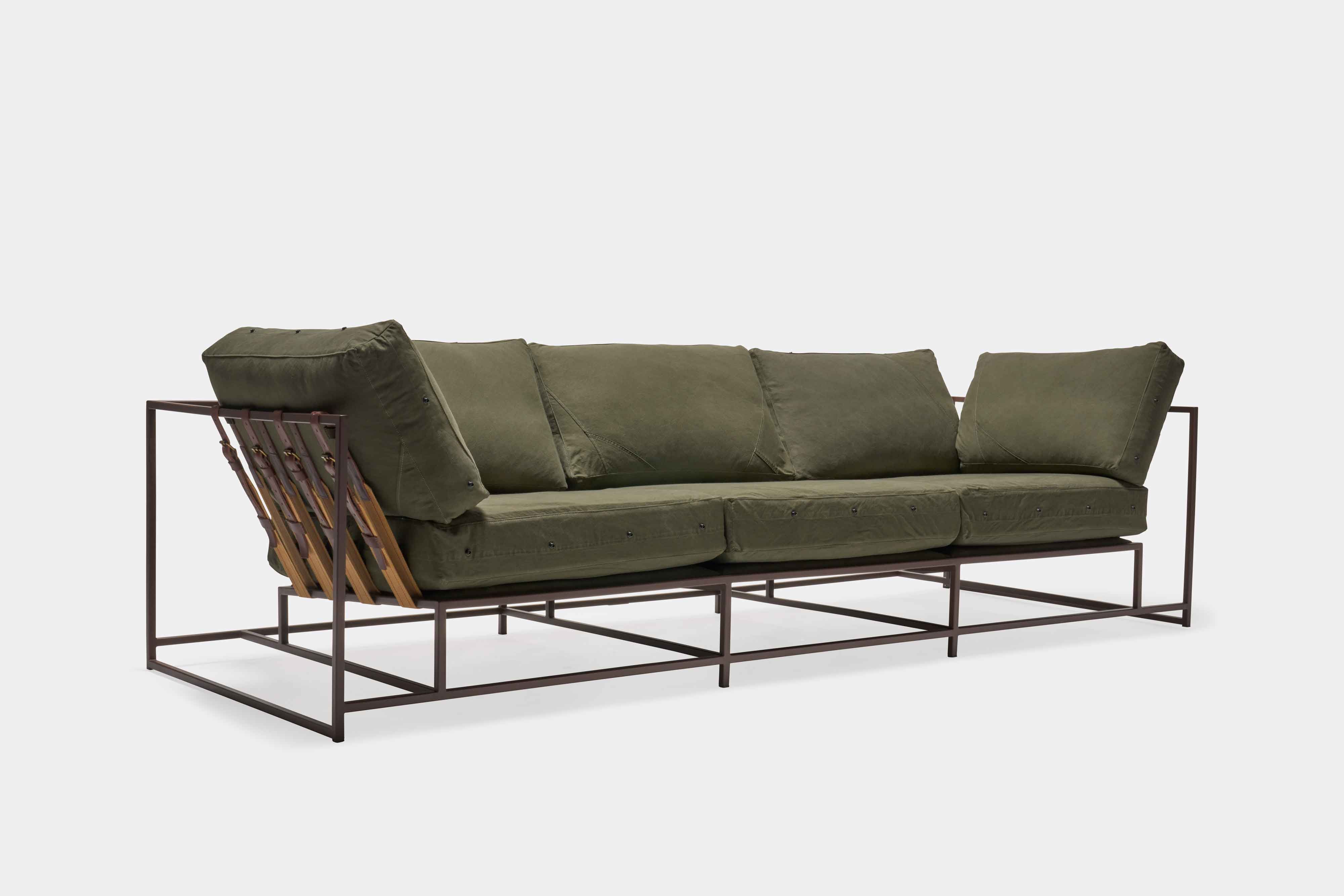 a green couch with a metal frame and leather straps