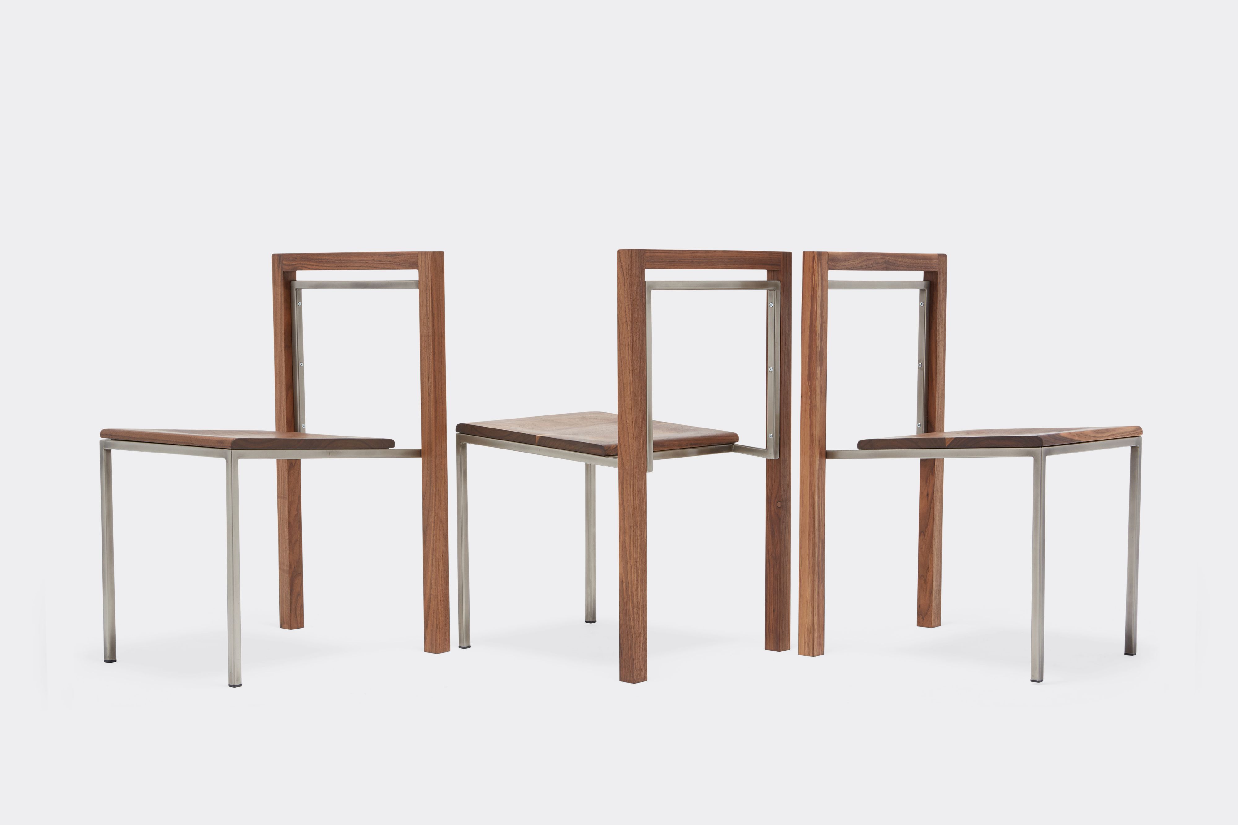 Three walnut and antique nickel dining chairs in a row positioned at varying angles