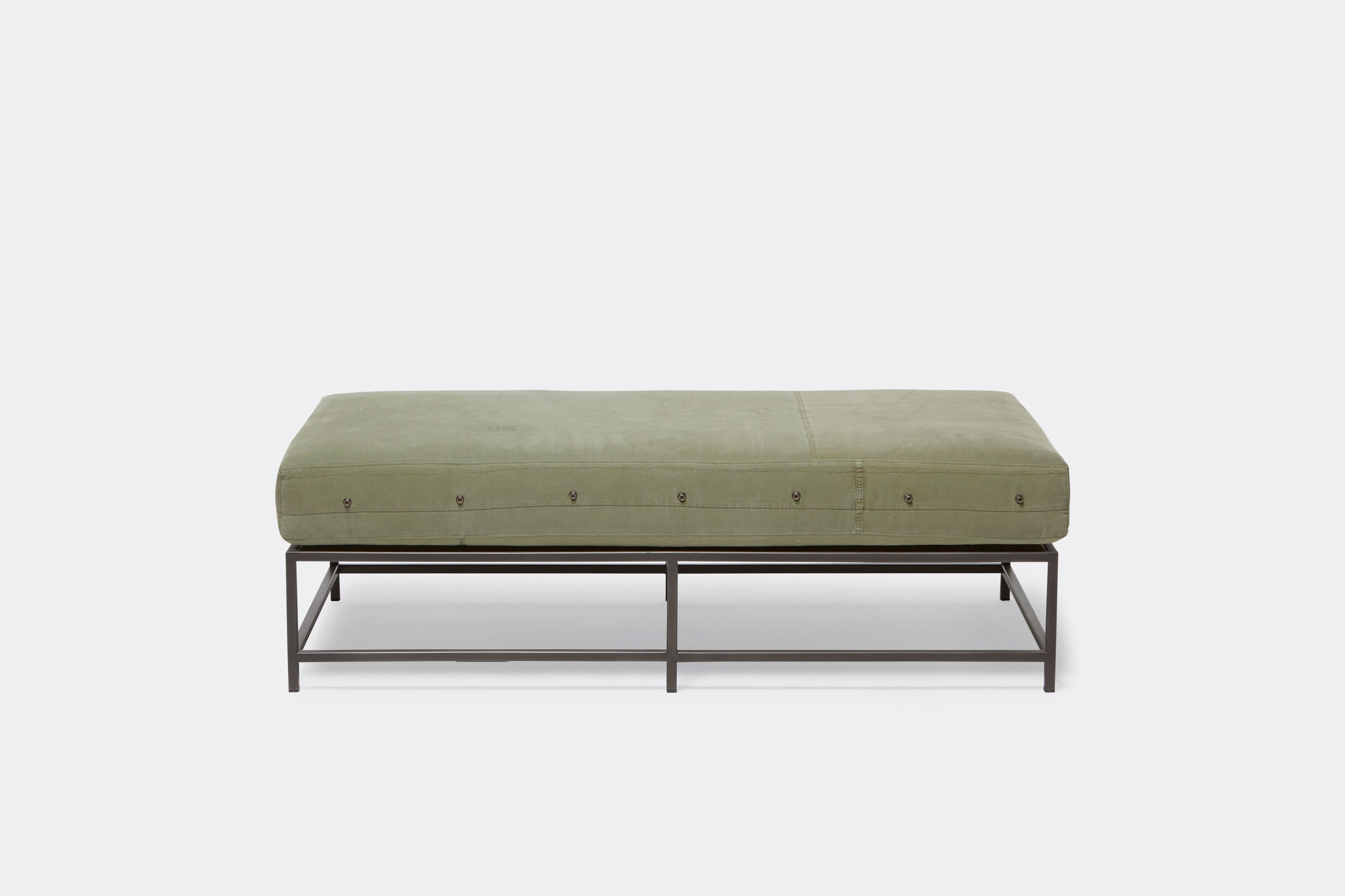 front of bench with green canvas upholstery on black metal frame.