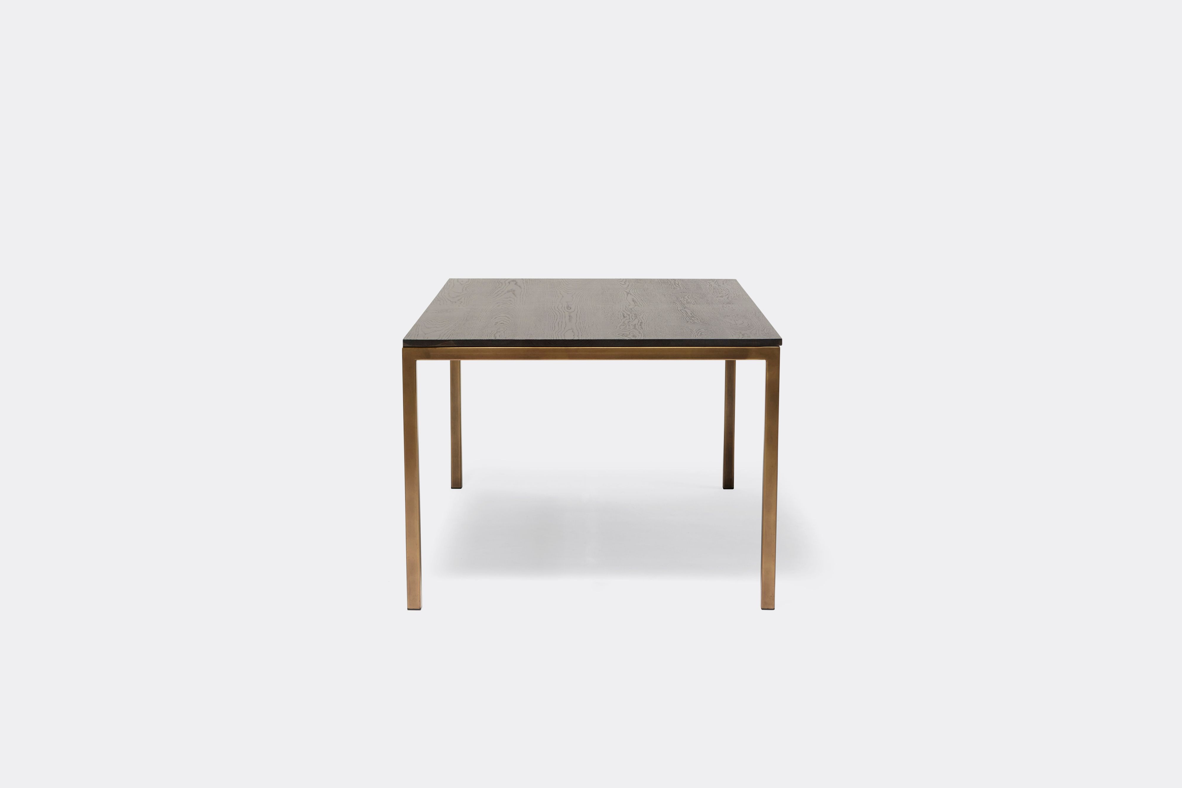 Front view of dining table with ebonized oak wood top and antique brass metal legs