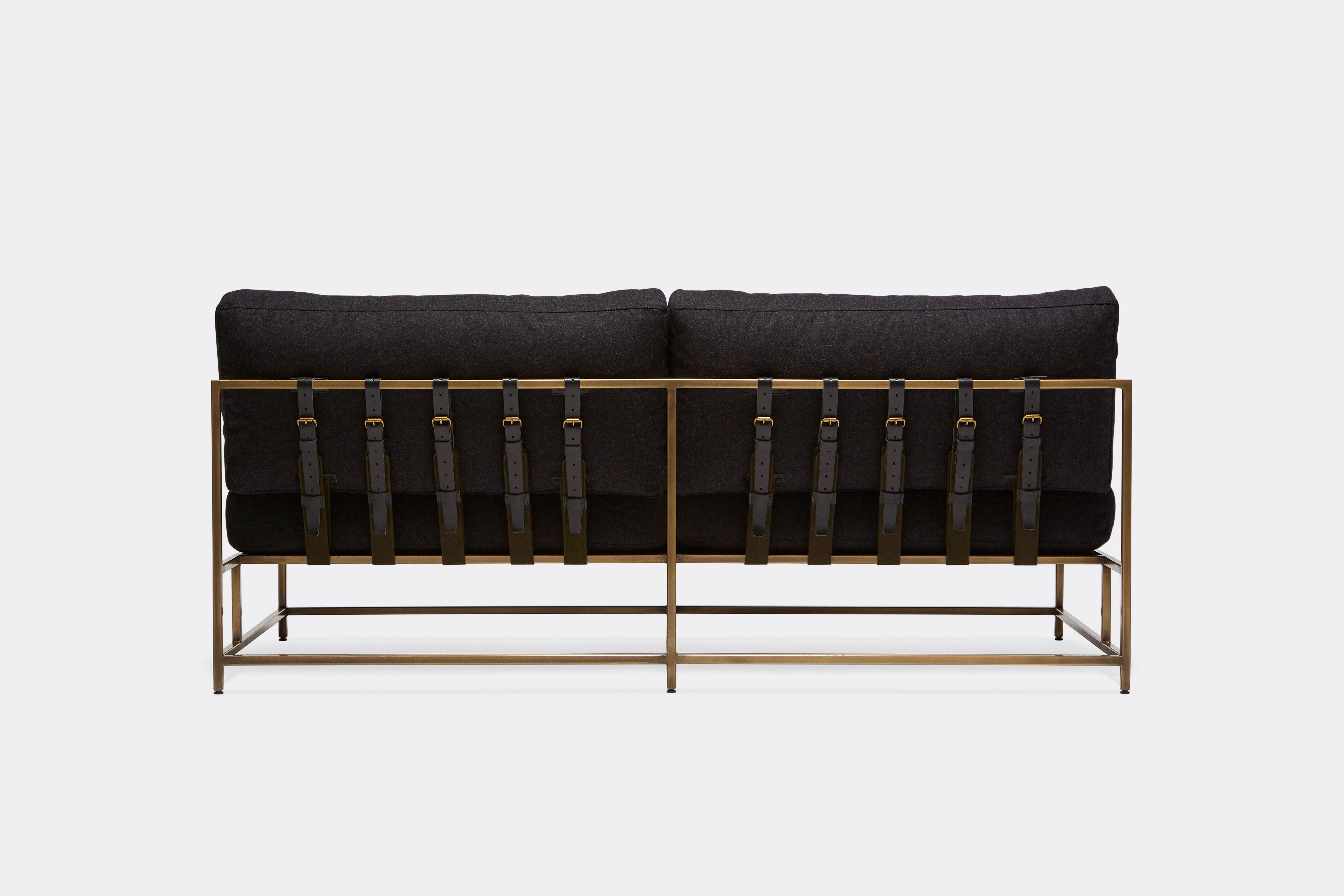 back of loveseat with black wool upholstery and black leather belts on antique brass metal frame