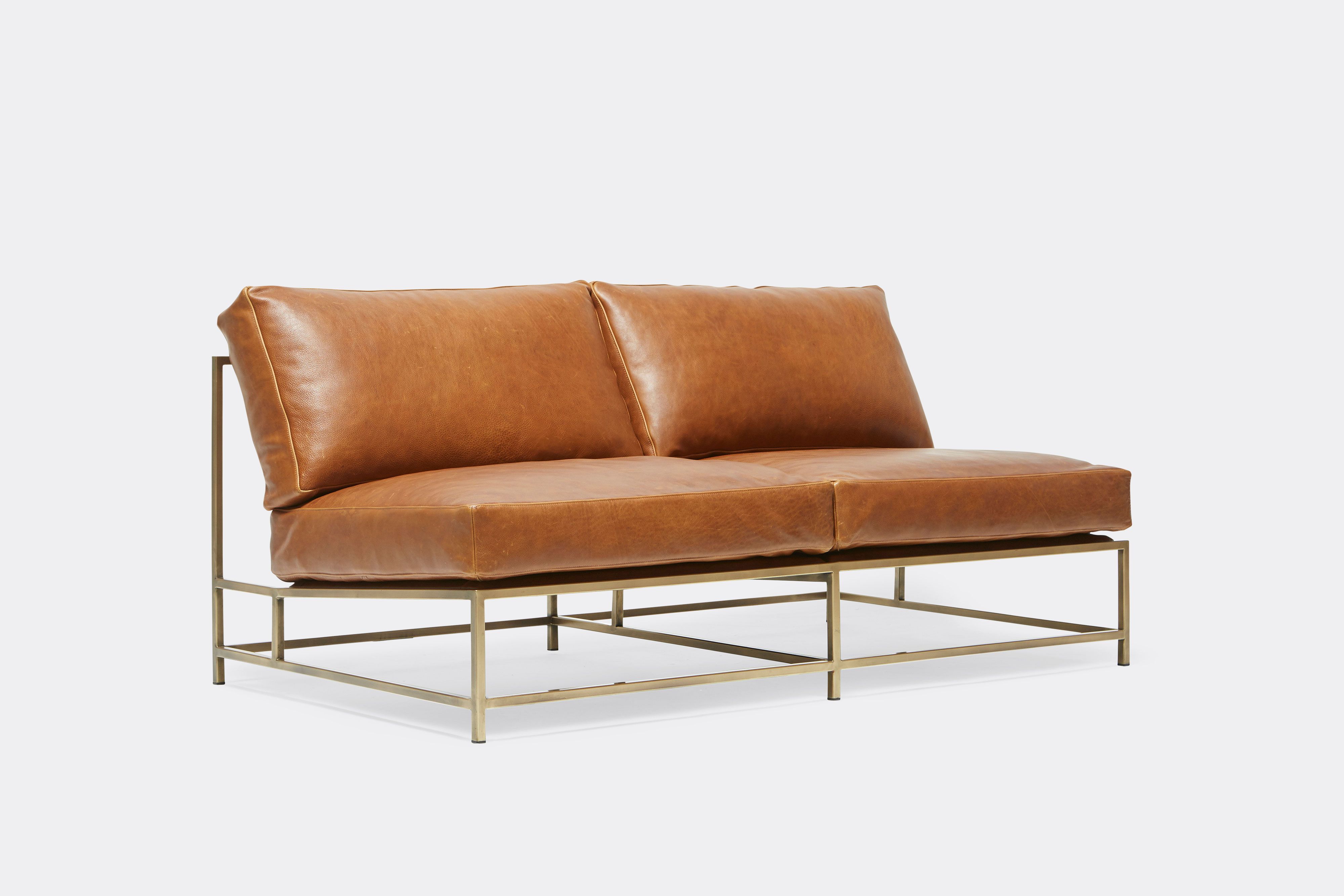 side of loveseat with brown leather upholstery and brown leather belts on antique brass metal frame