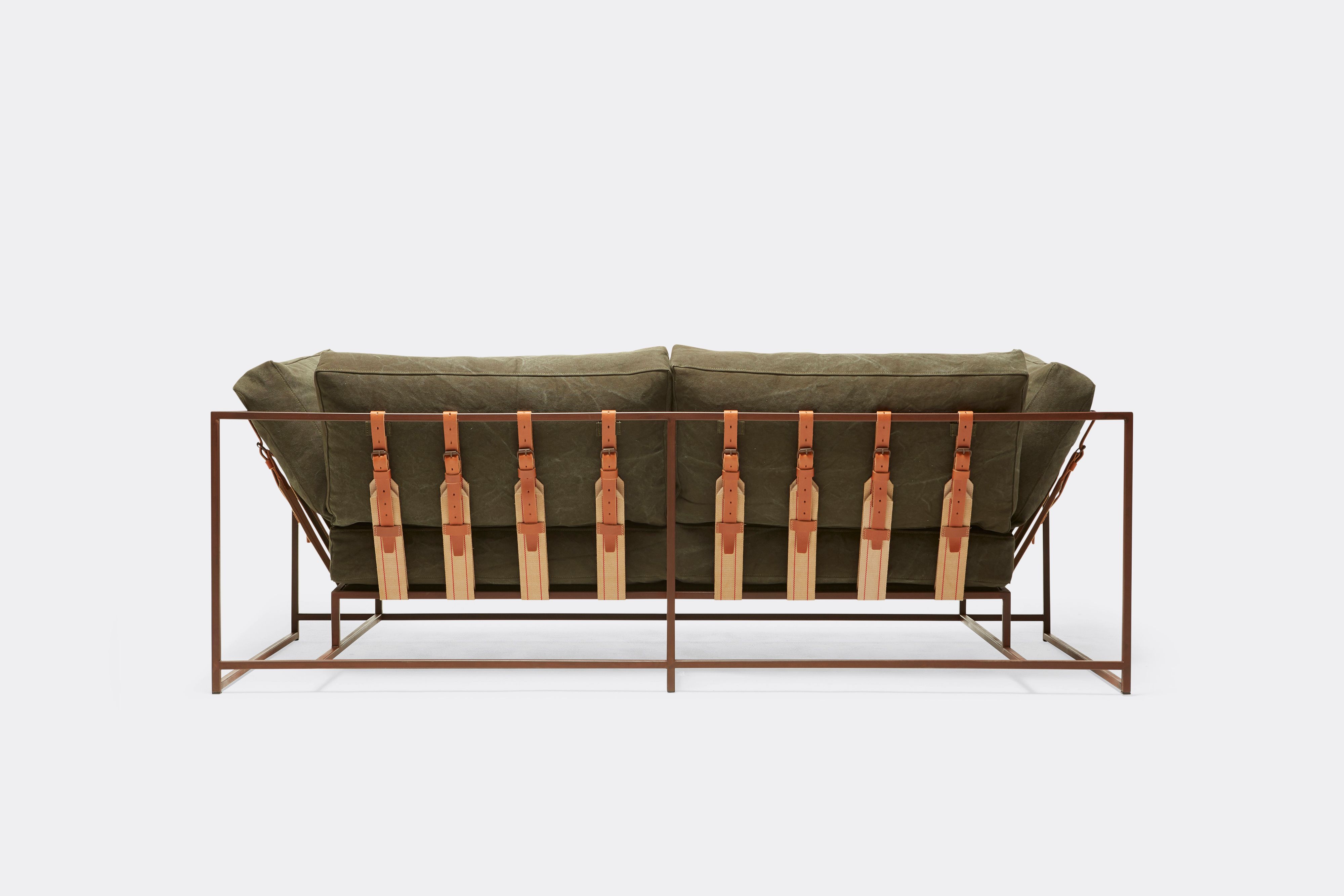 back of two seat sofa with olive canvas upholstery and brown leather belts on marbled rust metal frame