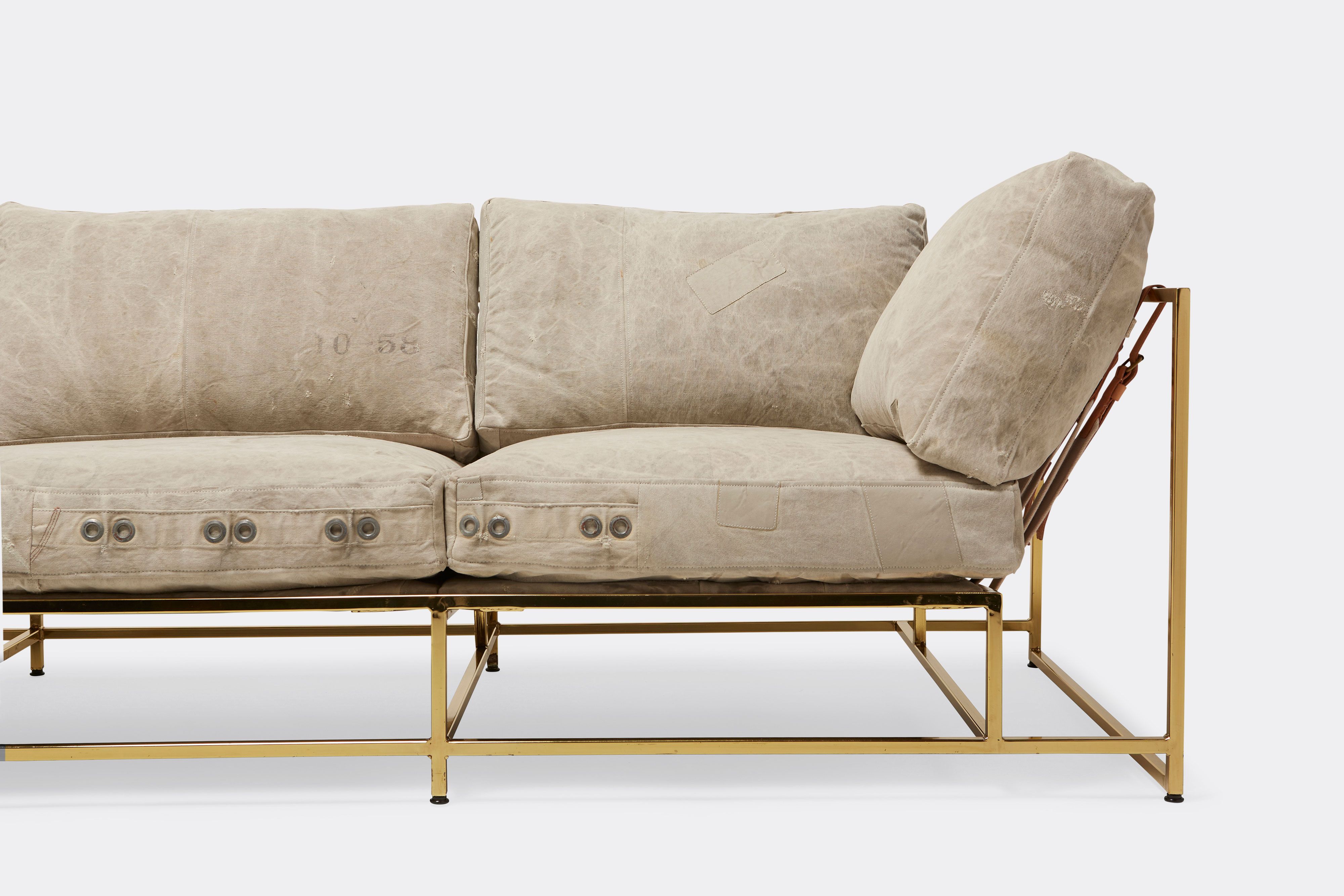 front detail of sofa with grey canvas upholstery on polished brass metal frame