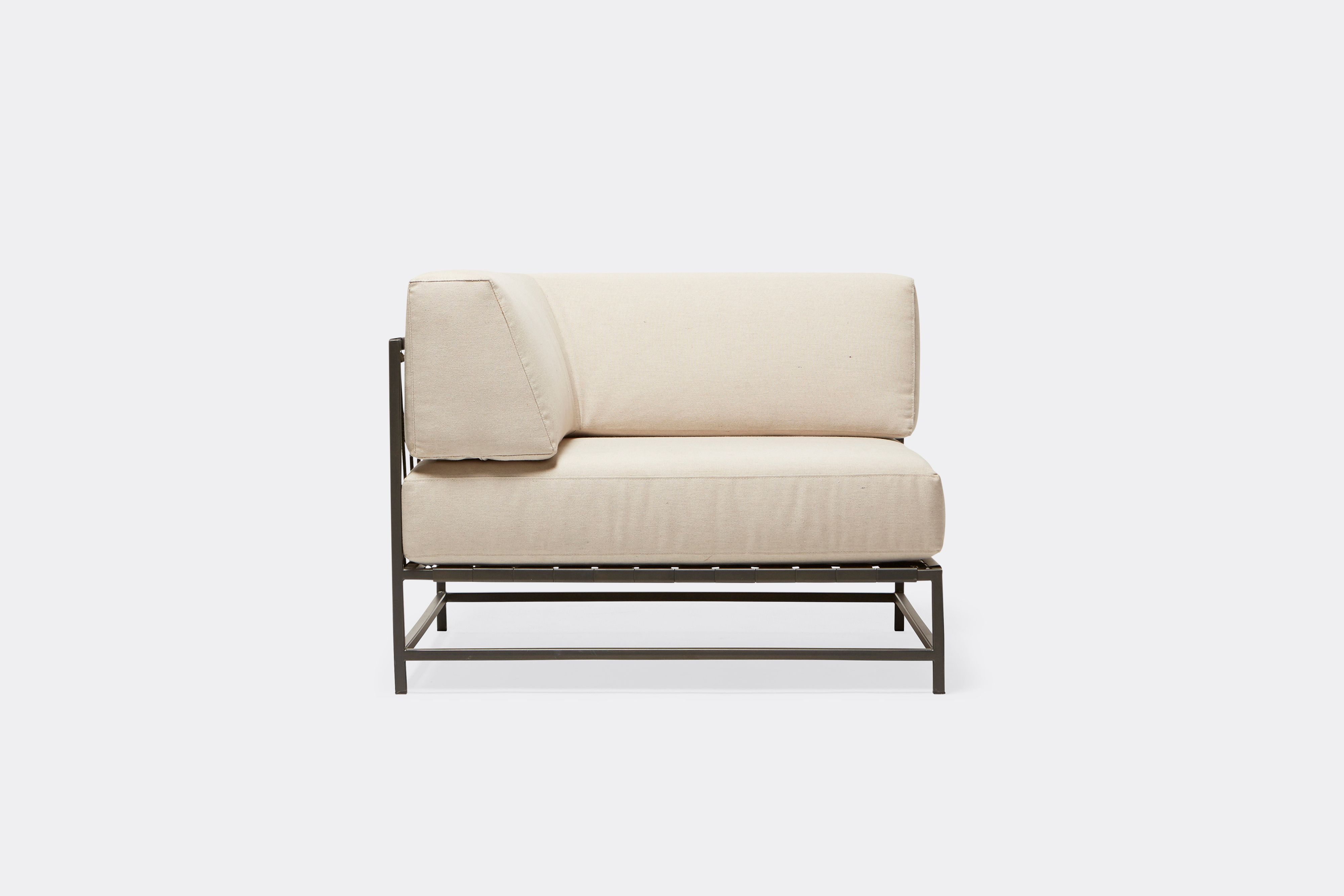 side of outdoor corner chair with cream canvas upholstery on dark grey metal frame