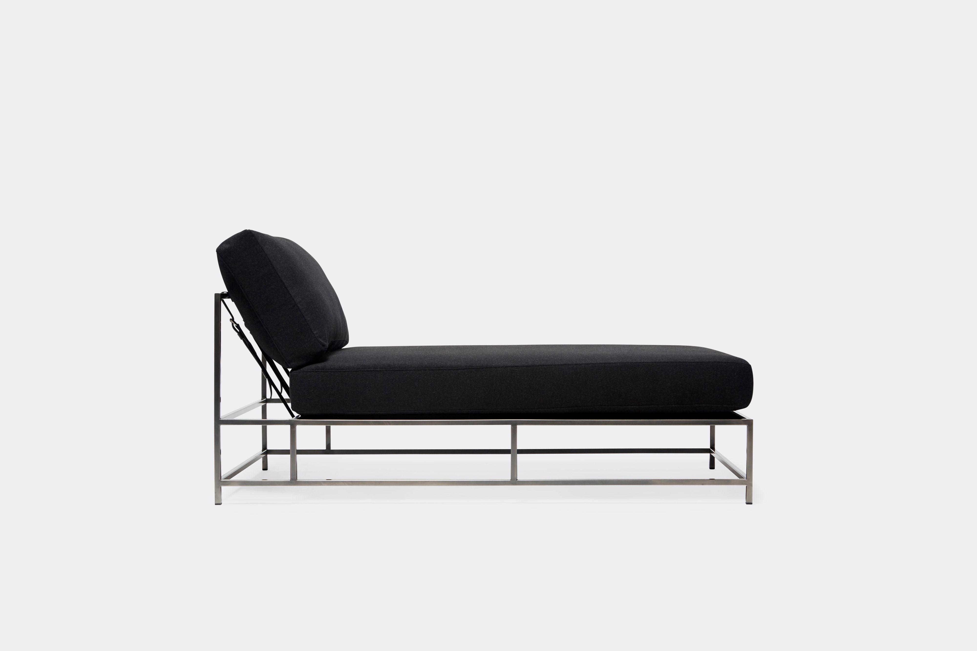 side of chaise lounge with black wool upholstery and black leather belts on antique nickel metal frame