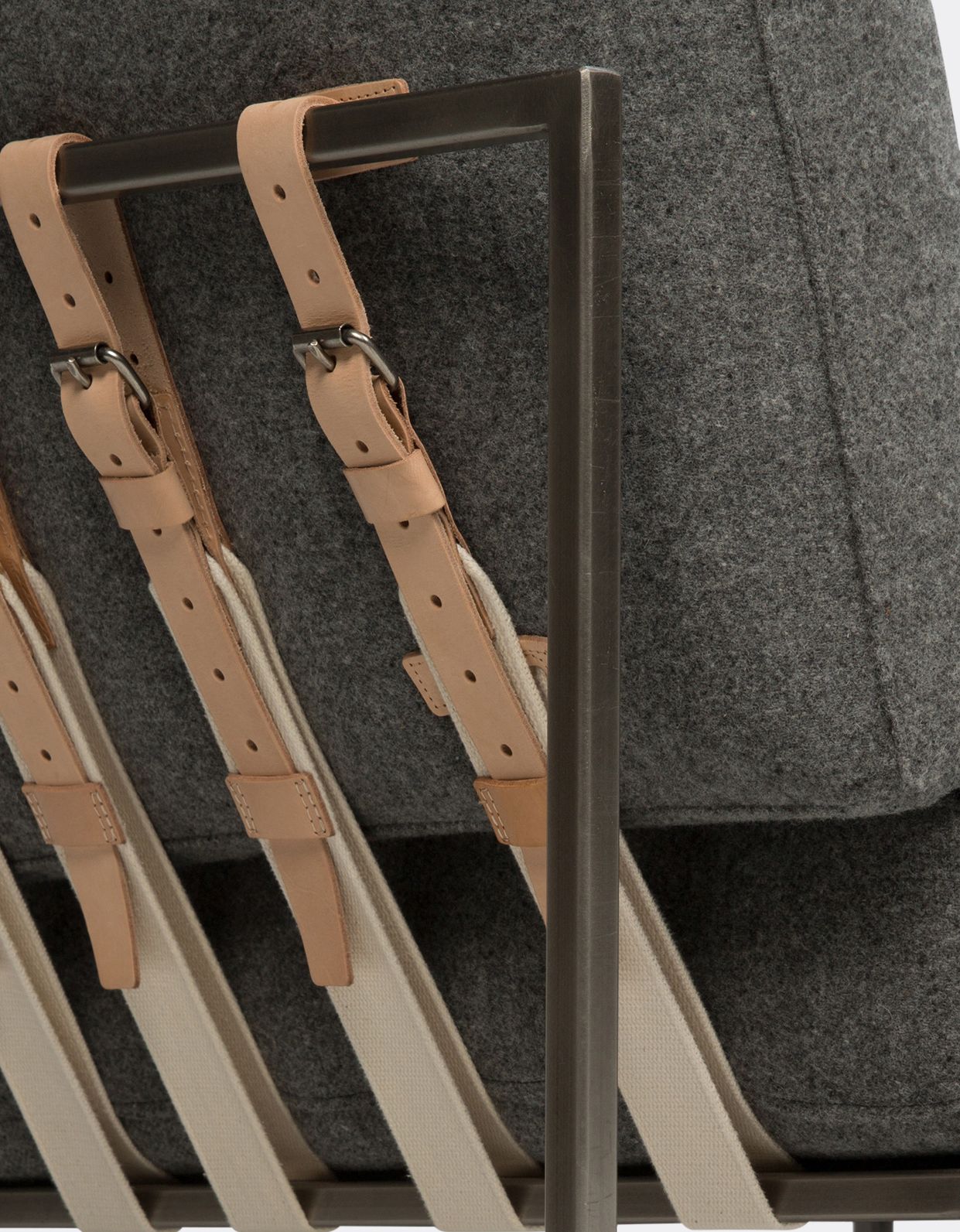 a steel framed sofa with grey wool upholstery and leather and webbing supporting belts shown on a white background