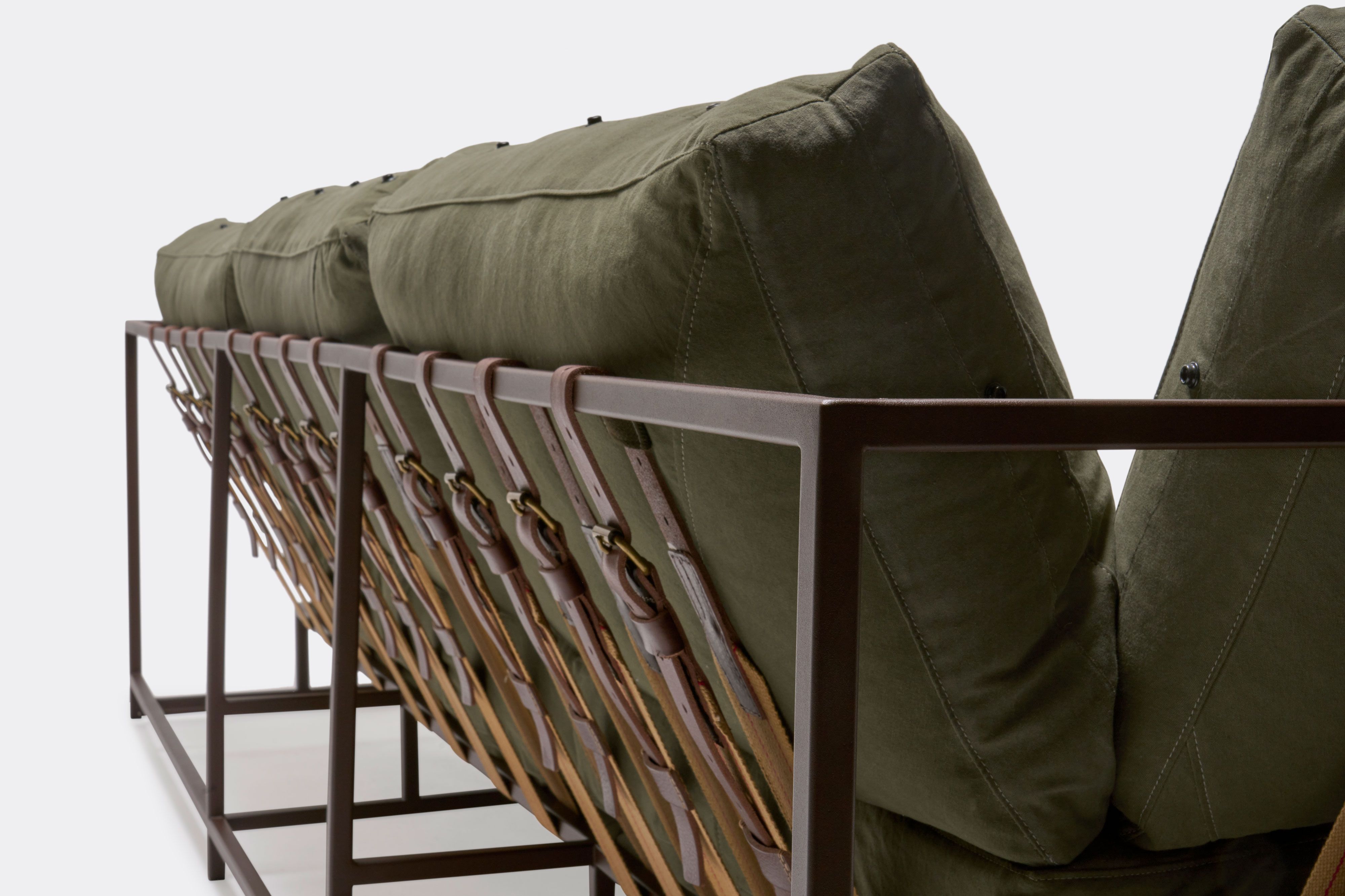 a green couch with a metal frame and leather straps