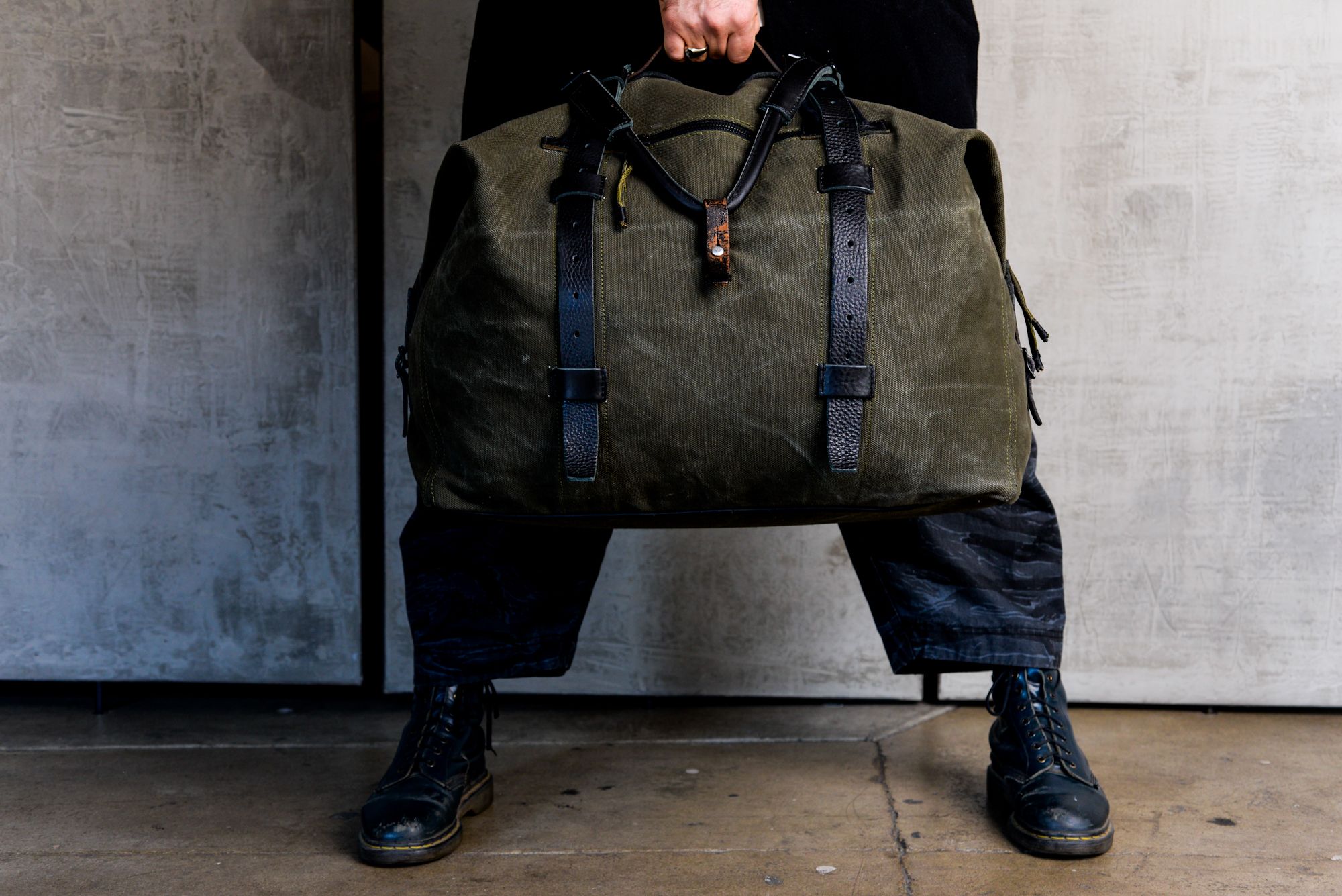 a person is holding a large green duffel bag in front of them