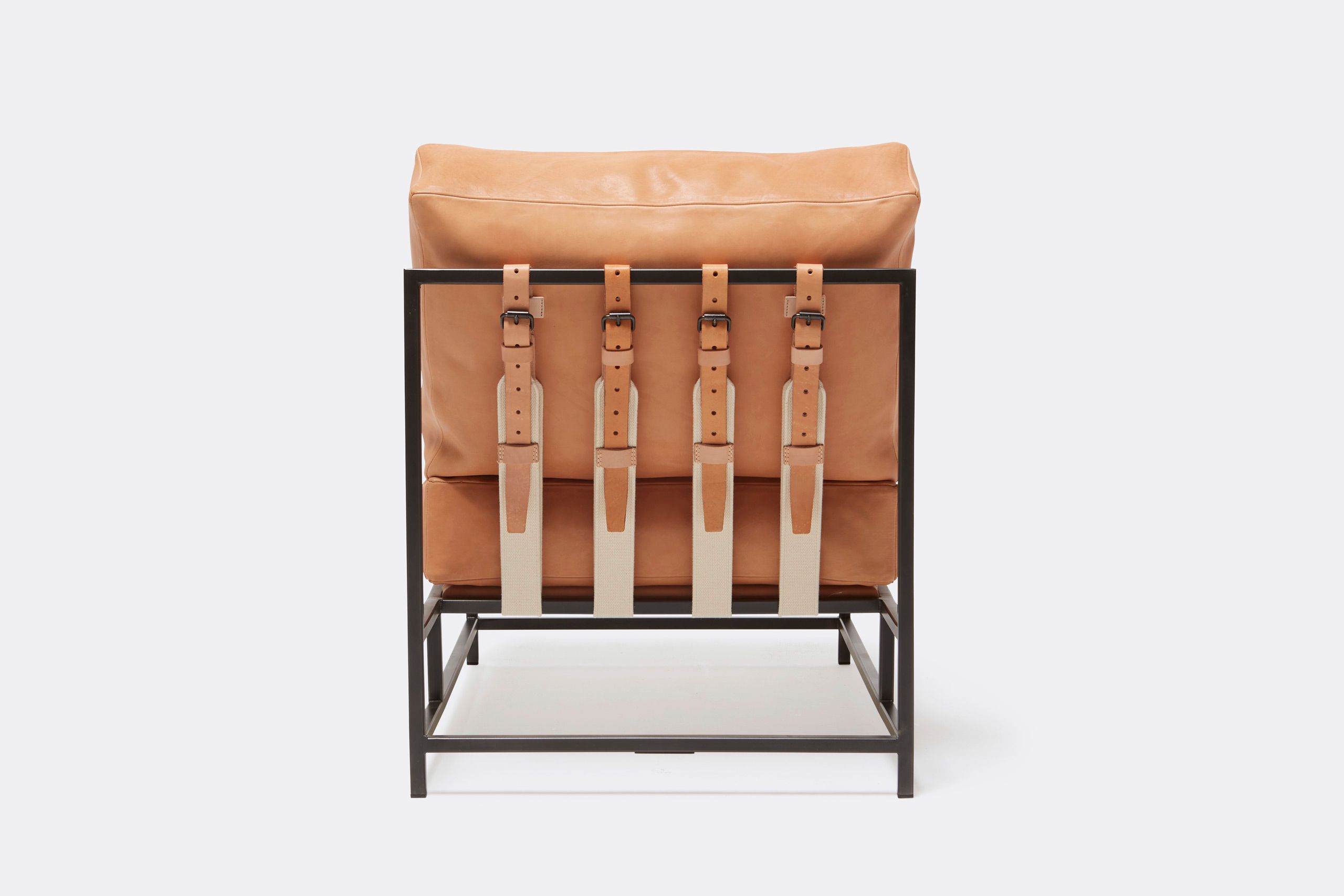 a tan leather chair with a metal frame and leather and webbing supporting belts shown on a white background .