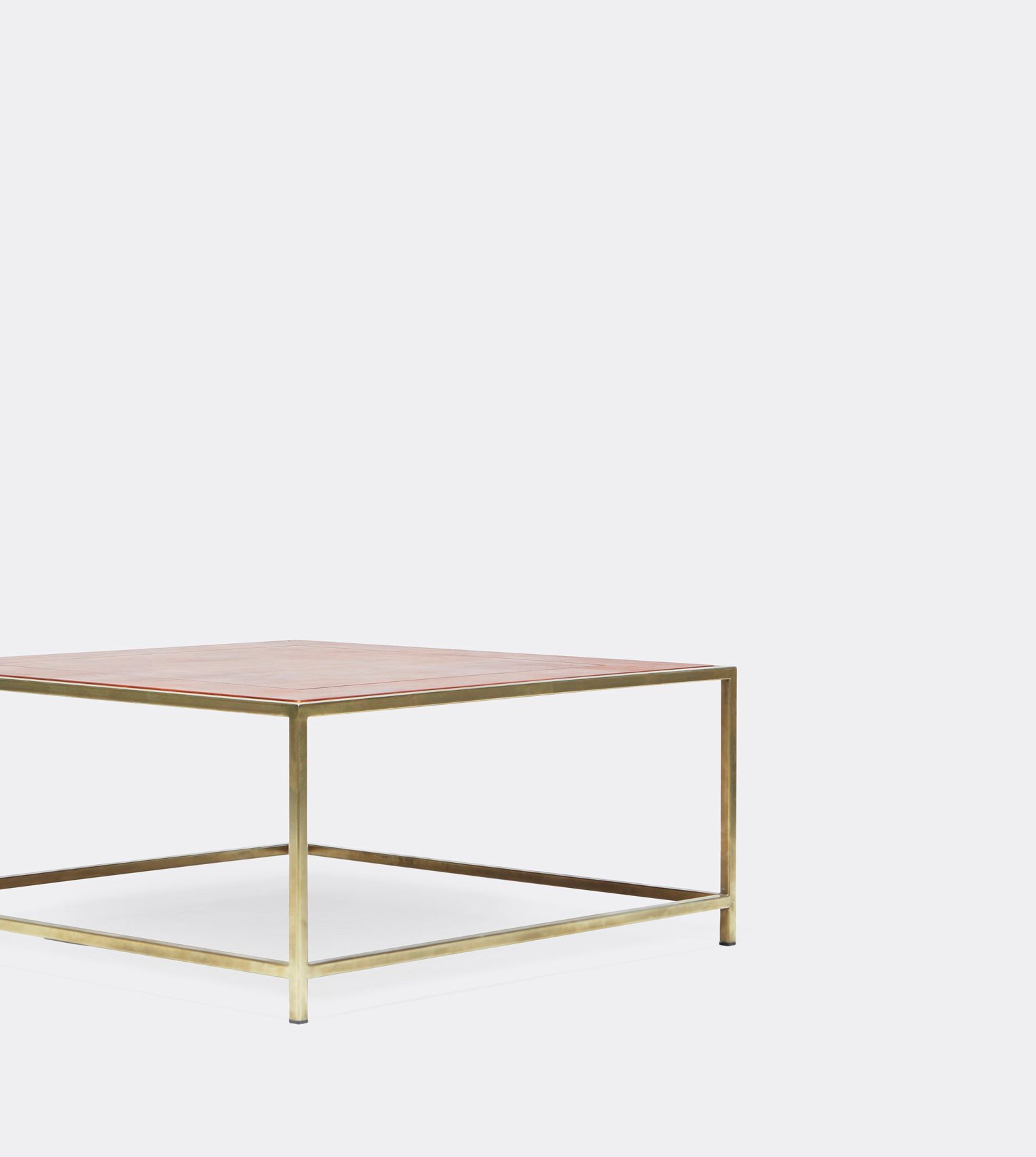 a square coffee table with a leather top and a brass frame on a white background .