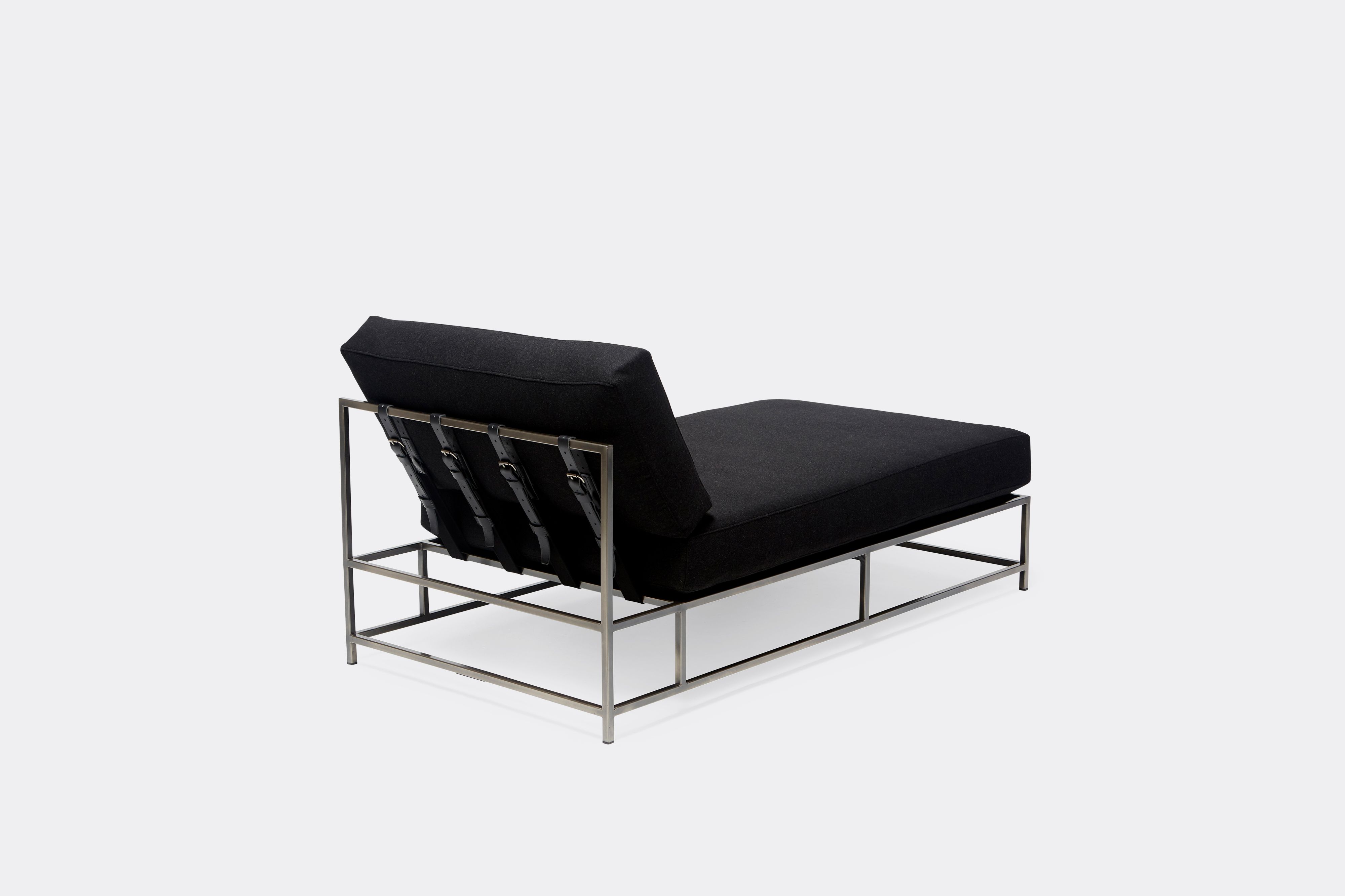 back of chaise lounge with black wool upholstery and black leather belts on antique nickel metal frame