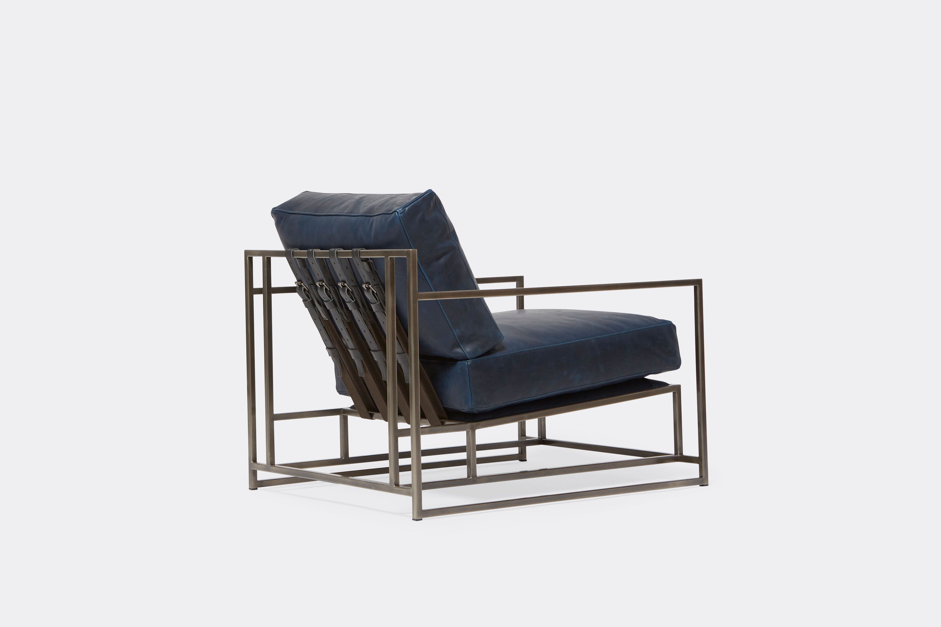 side of armchair with blue leather upholstery and black leather belts on antique nickel metal frame